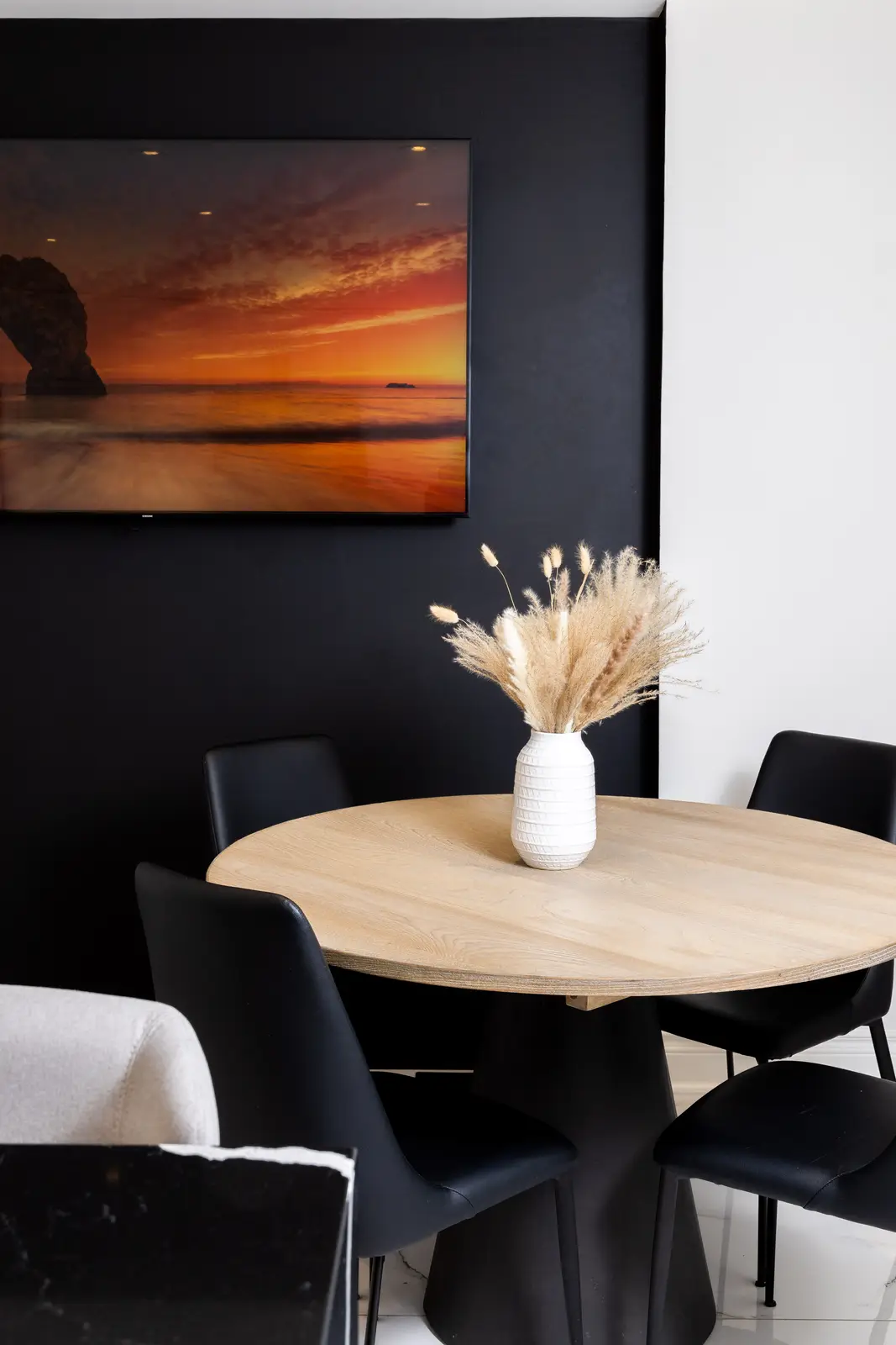 Interior of an Oakville house, with a dark dining table, light wood floors, and a white living room.