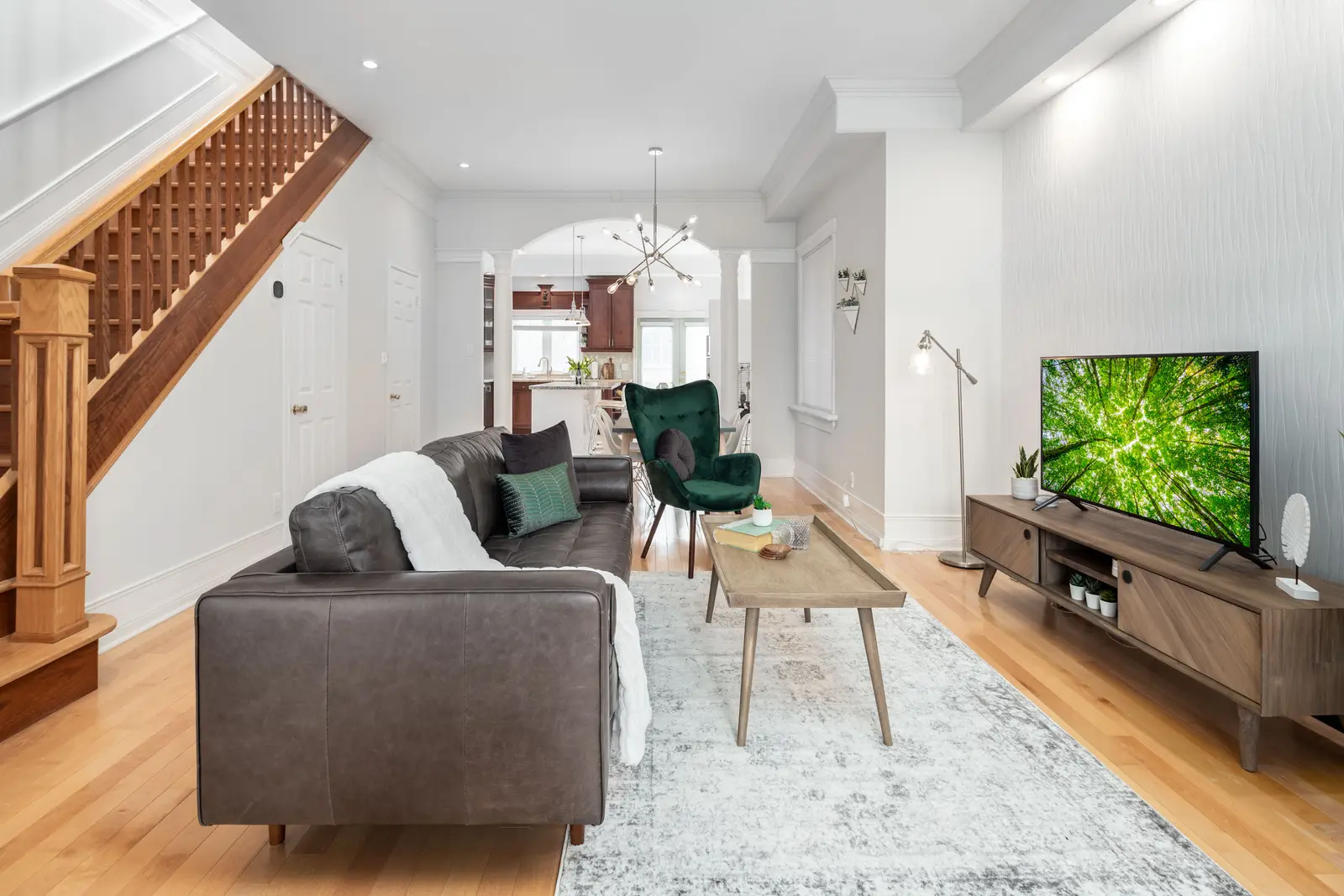 Interior of a Toronto house, with light walls, a wood kitchen, and a grey sofa.