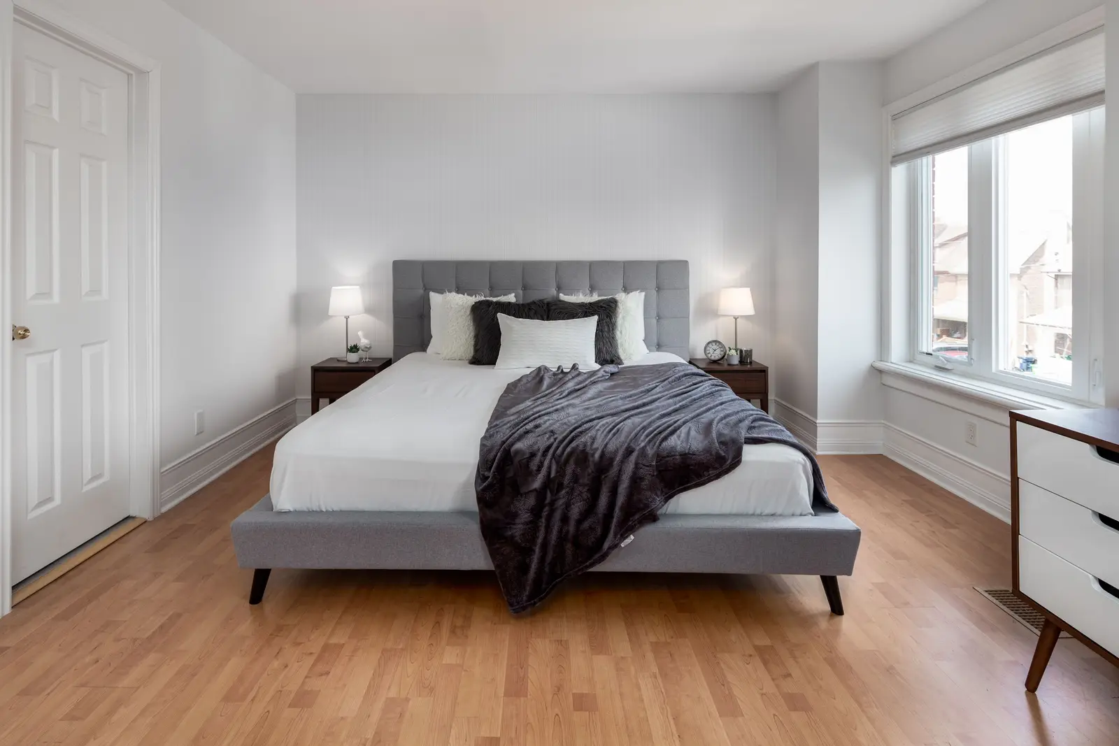 Interior of a Toronto house, with light walls, a wood kitchen, and a grey sofa.