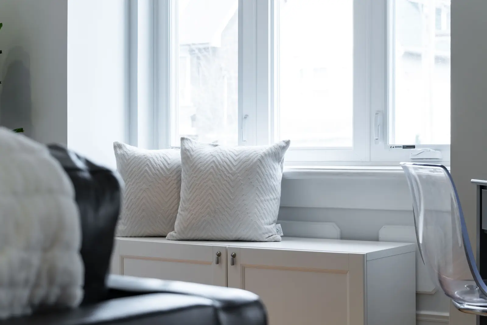 Interior of a Toronto house, with light walls, a wood kitchen, and a grey sofa.
