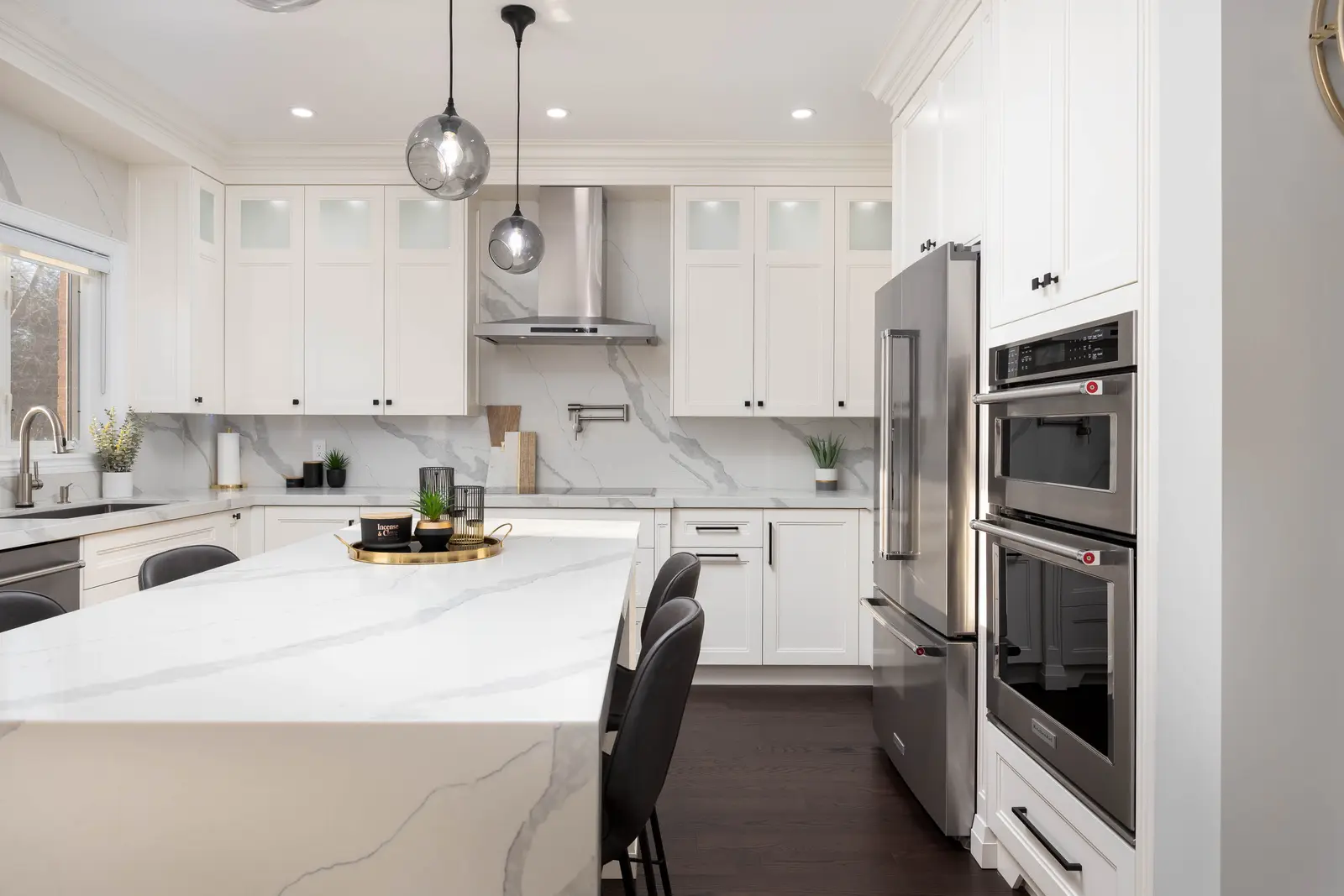 Interior of a Vaughan house, with white cabinetry, dark wood floors, and marble.