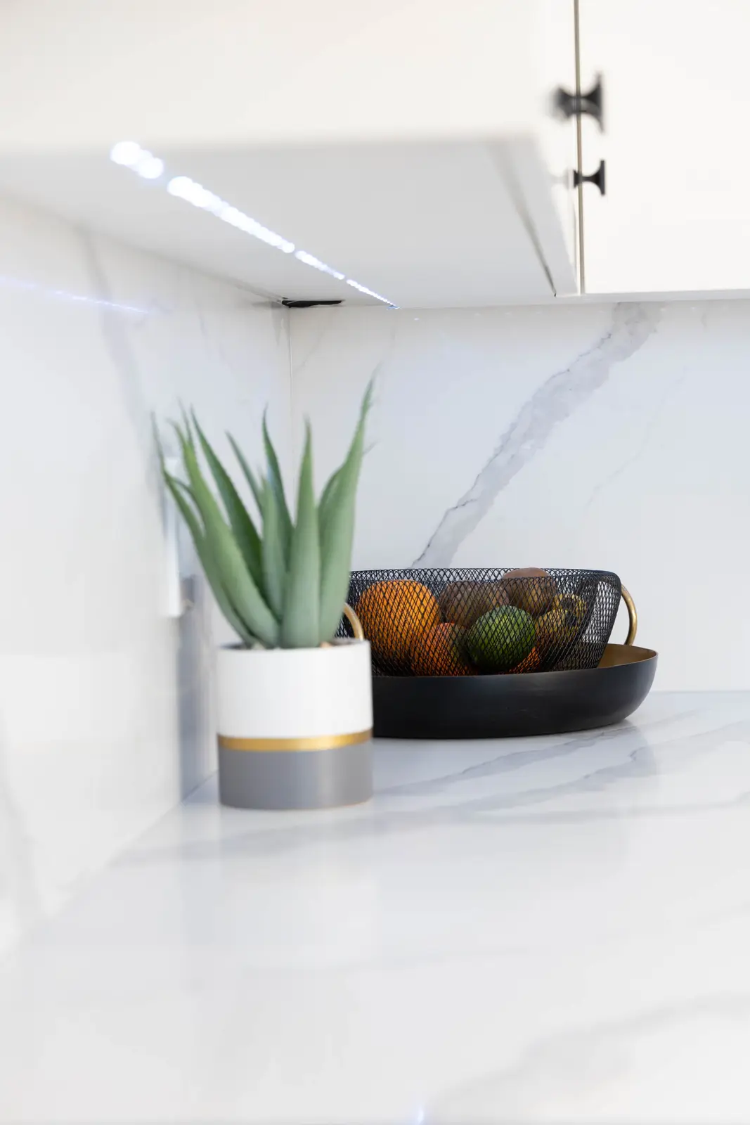 Interior of a Vaughan house, with white cabinetry, dark wood floors, and marble.