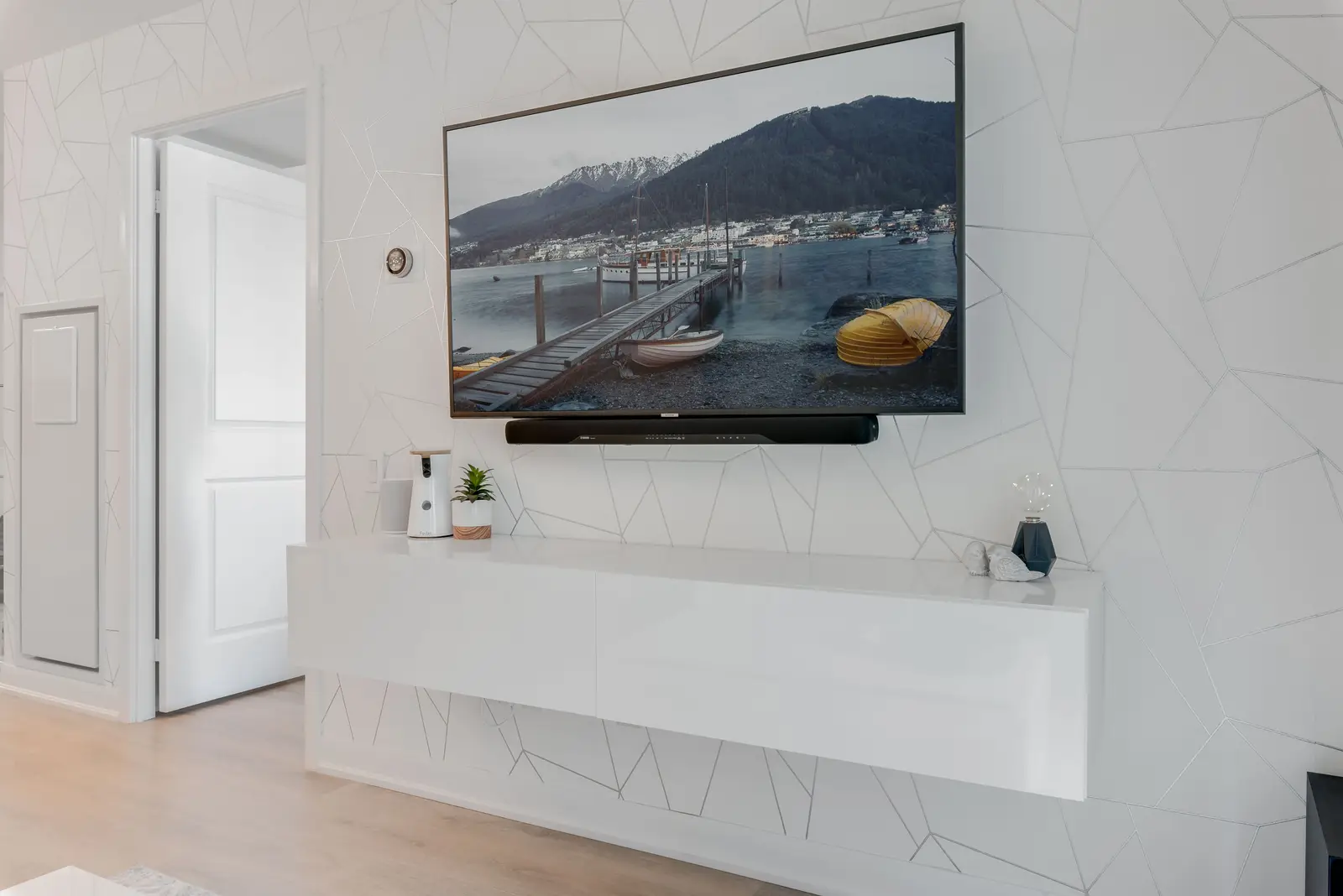 Interior of a North York condo, with a pale sofa, a white kitchen, and light wood floors.