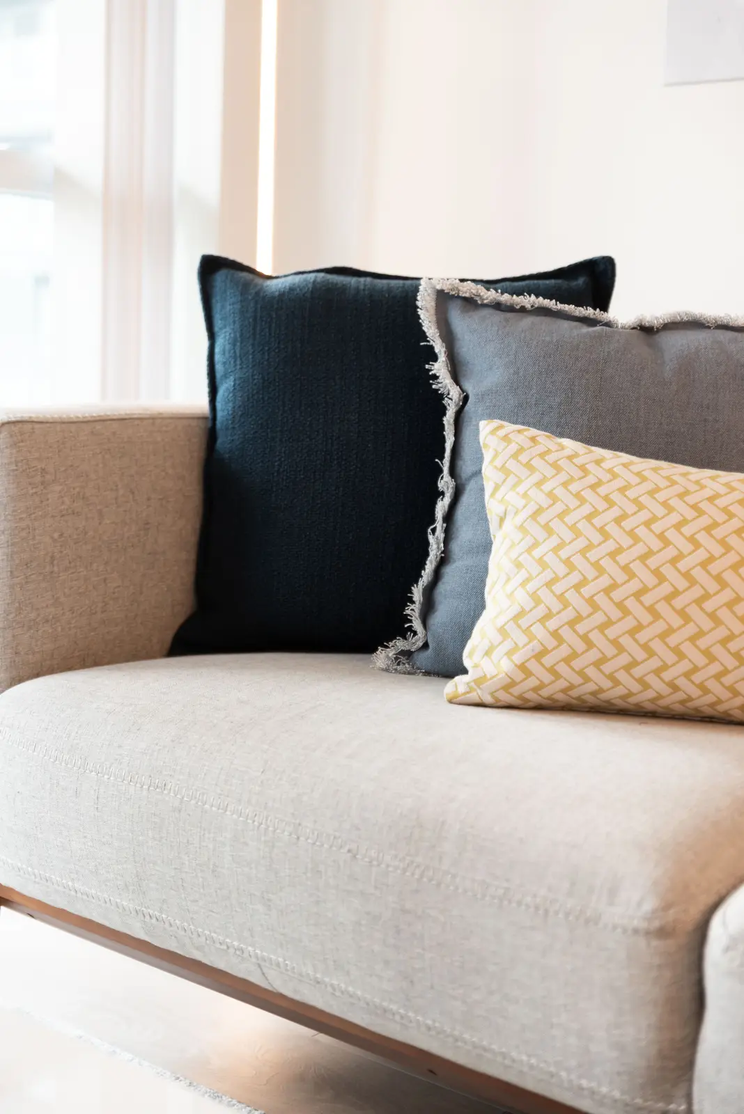 Interior of a North York condo, with a pale sofa, a white kitchen, and light wood floors.