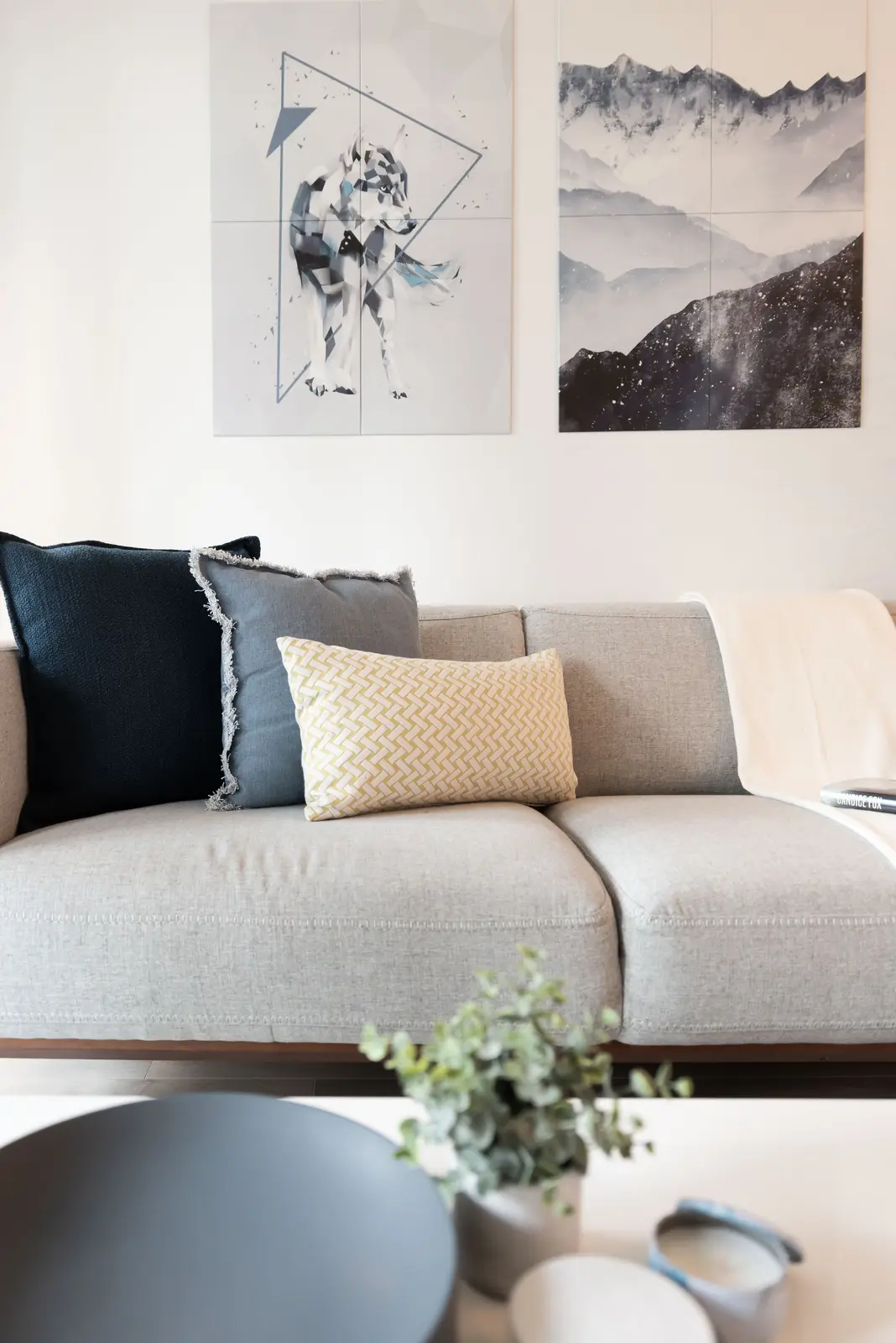 Interior of a North York condo, with a pale sofa, a white kitchen, and light wood floors.