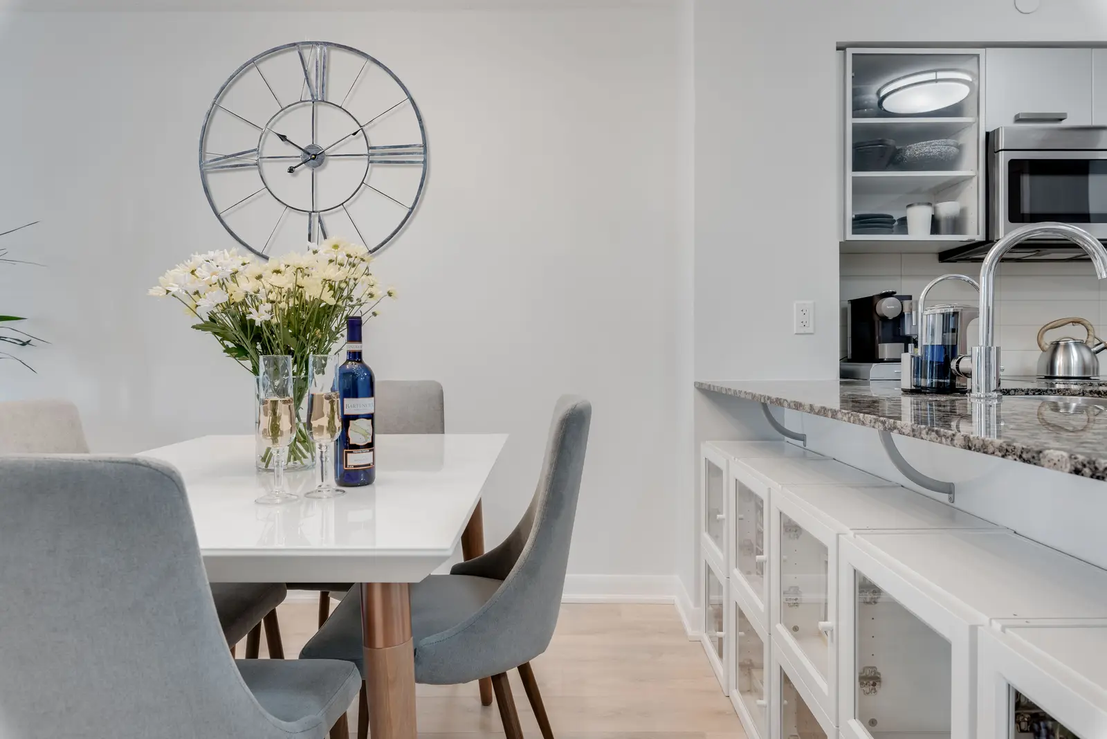 Interior of a North York condo, with a pale sofa, a white kitchen, and light wood floors.