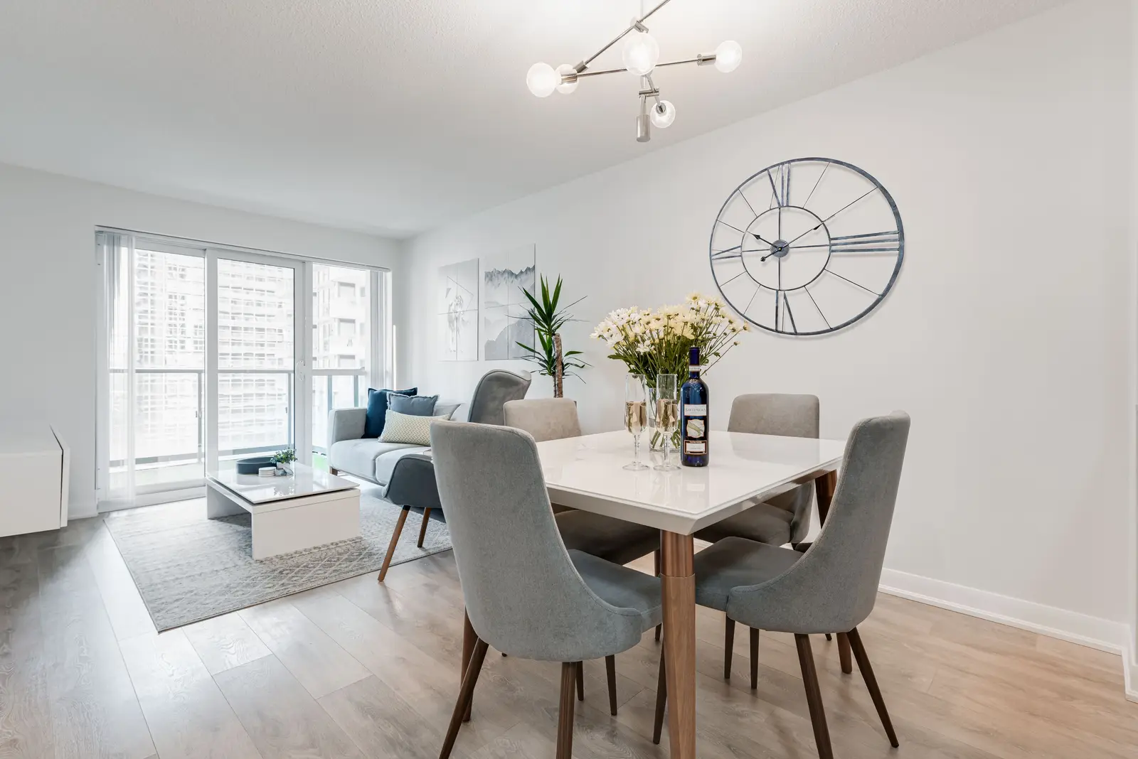 Interior of a North York condo, with a pale sofa, a white kitchen, and light wood floors.