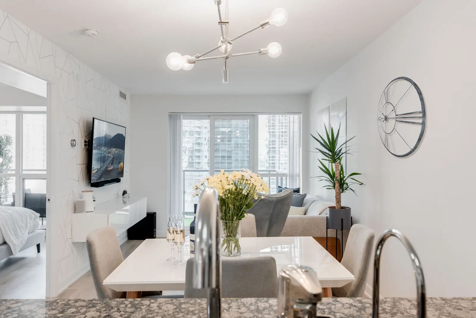 Interior of a North York condo, with a pale sofa, a white kitchen, and light wood floors.