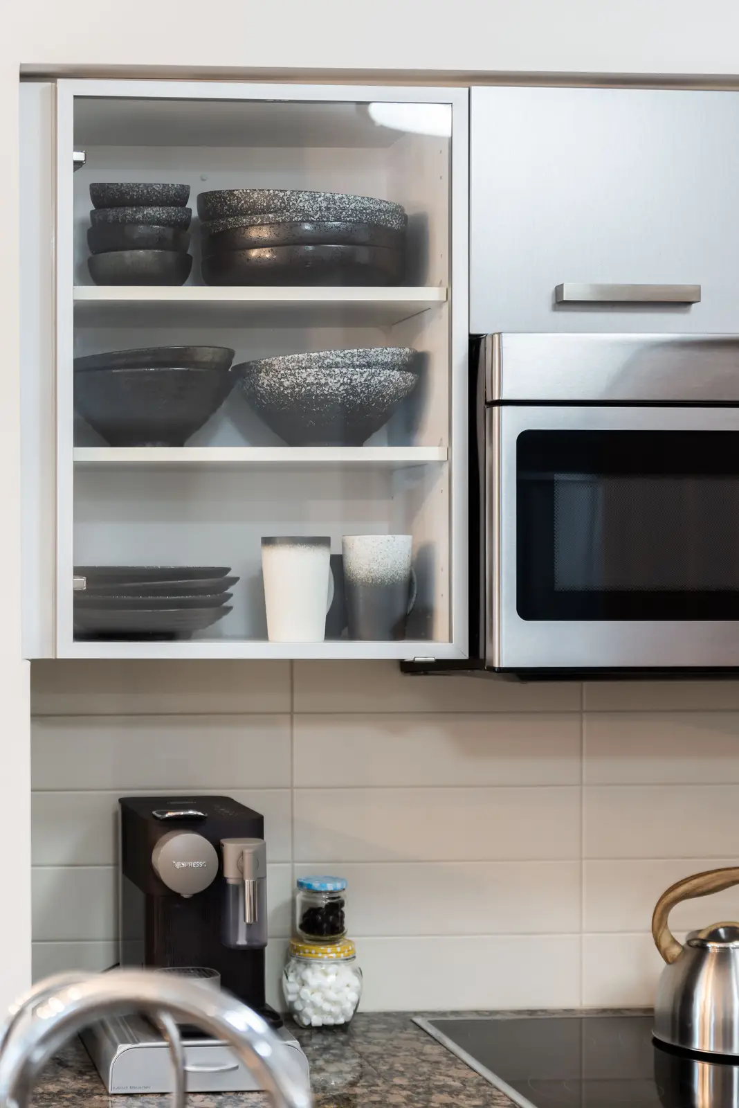 Interior of a North York condo, with a pale sofa, a white kitchen, and light wood floors.