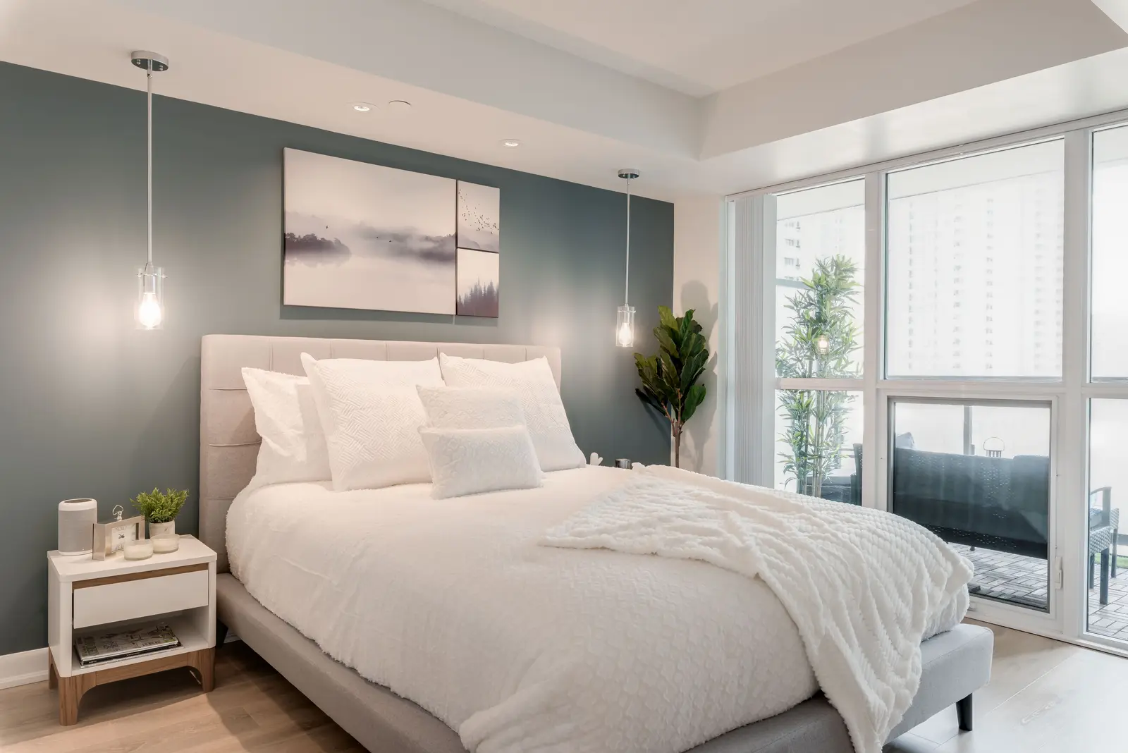 Interior of a North York condo, with a pale sofa, a white kitchen, and light wood floors.