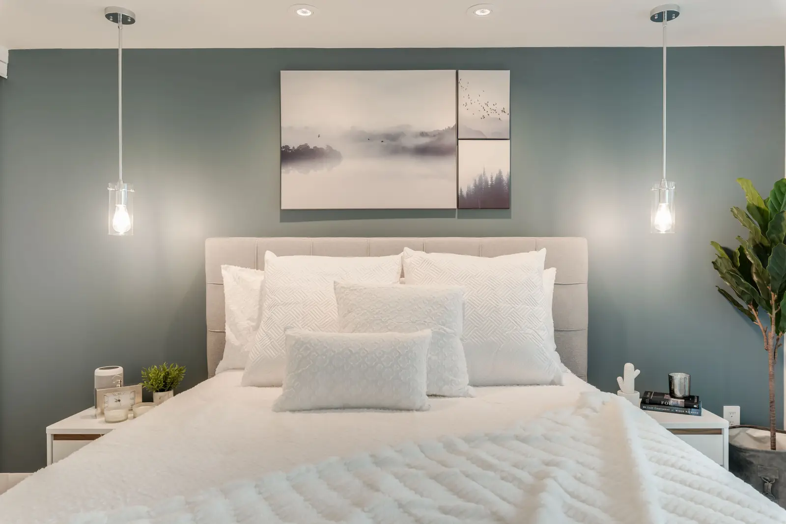Interior of a North York condo, with a pale sofa, a white kitchen, and light wood floors.