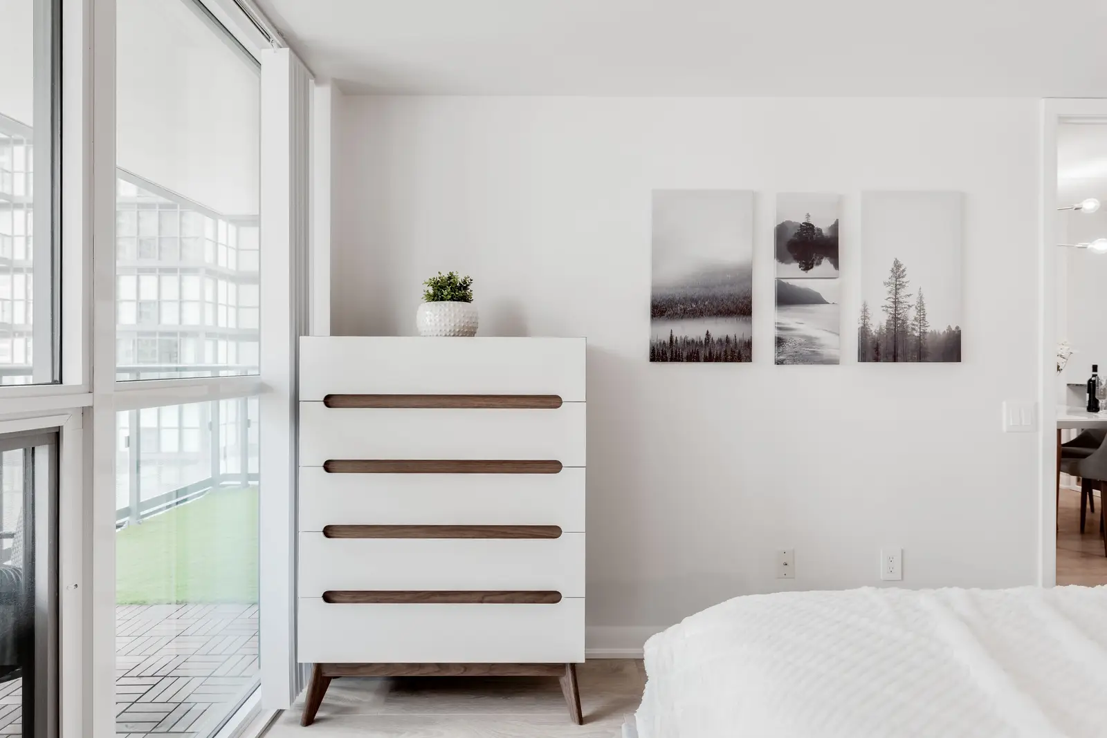 Interior of a North York condo, with a pale sofa, a white kitchen, and light wood floors.