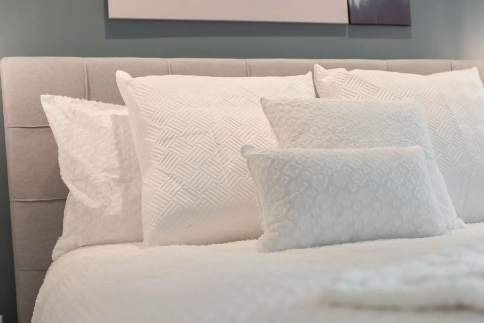 Interior of a North York condo, with a pale sofa, a white kitchen, and light wood floors.