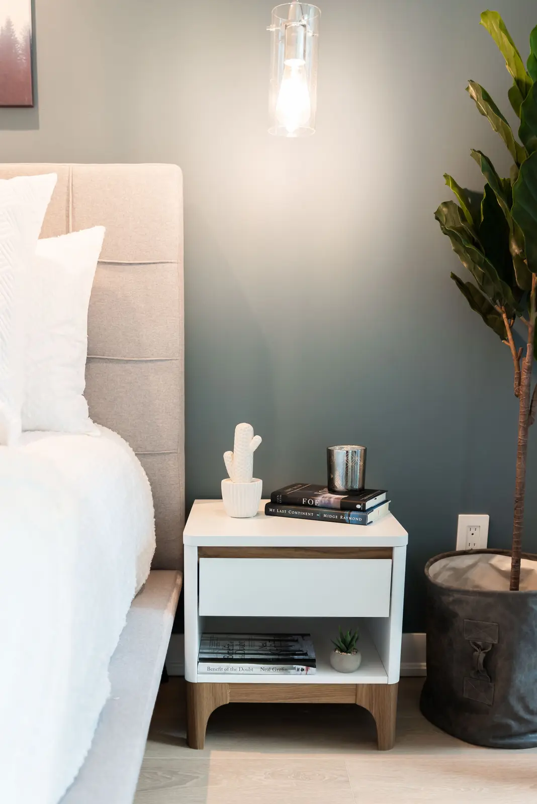 Interior of a North York condo, with a pale sofa, a white kitchen, and light wood floors.