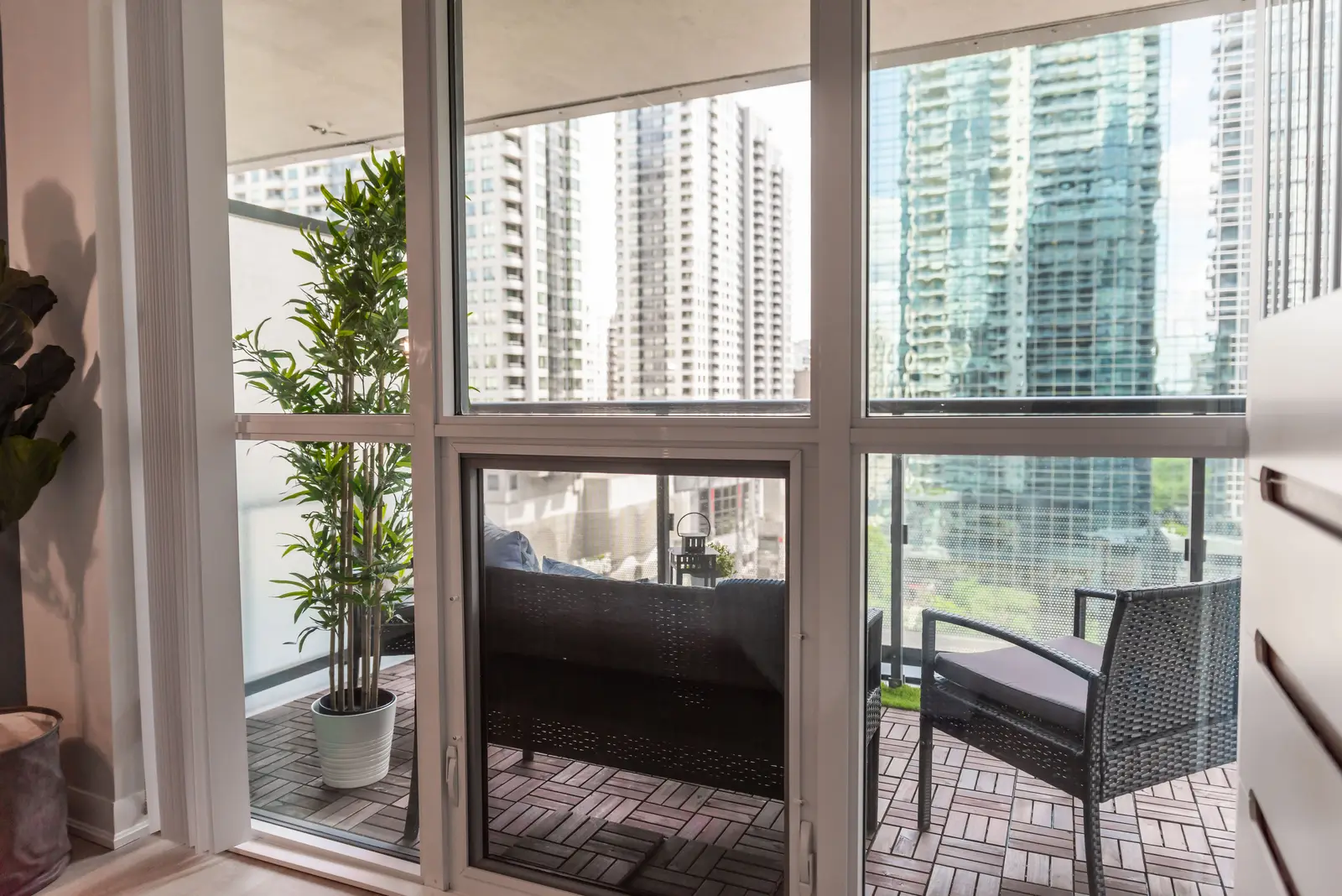 Interior of a North York condo, with a pale sofa, a white kitchen, and light wood floors.