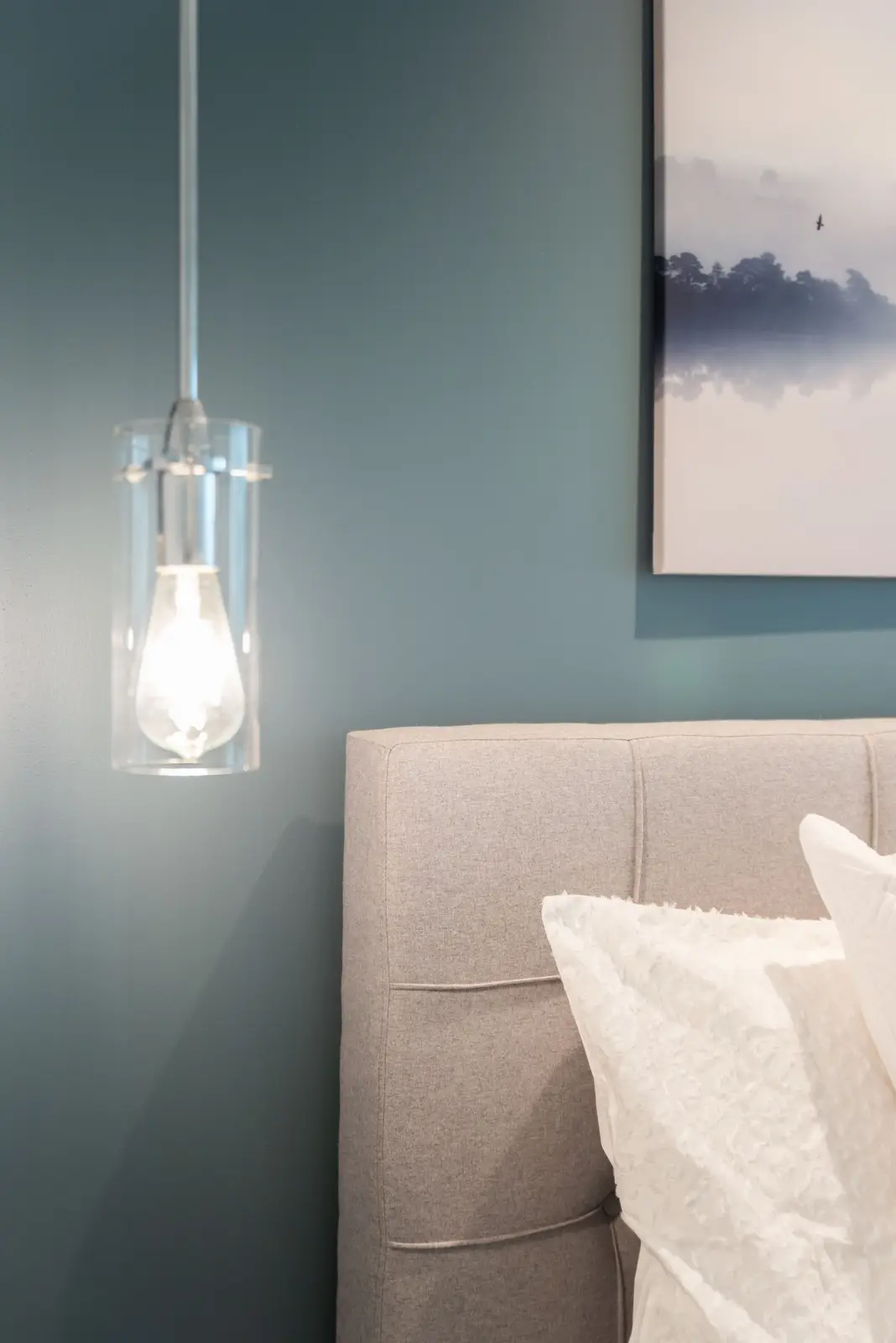 Interior of a North York condo, with a pale sofa, a white kitchen, and light wood floors.