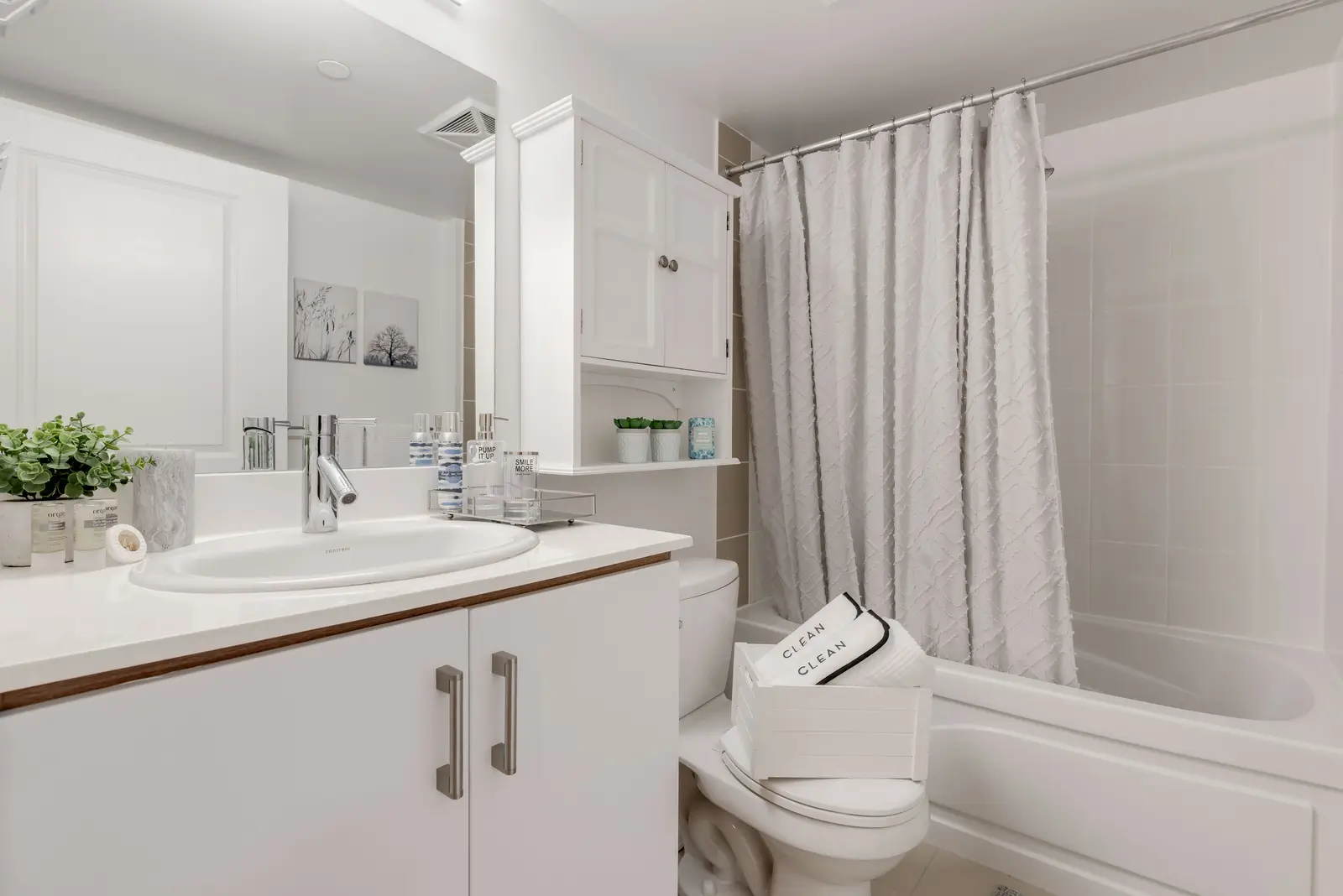 Interior of a North York condo, with a pale sofa, a white kitchen, and light wood floors.