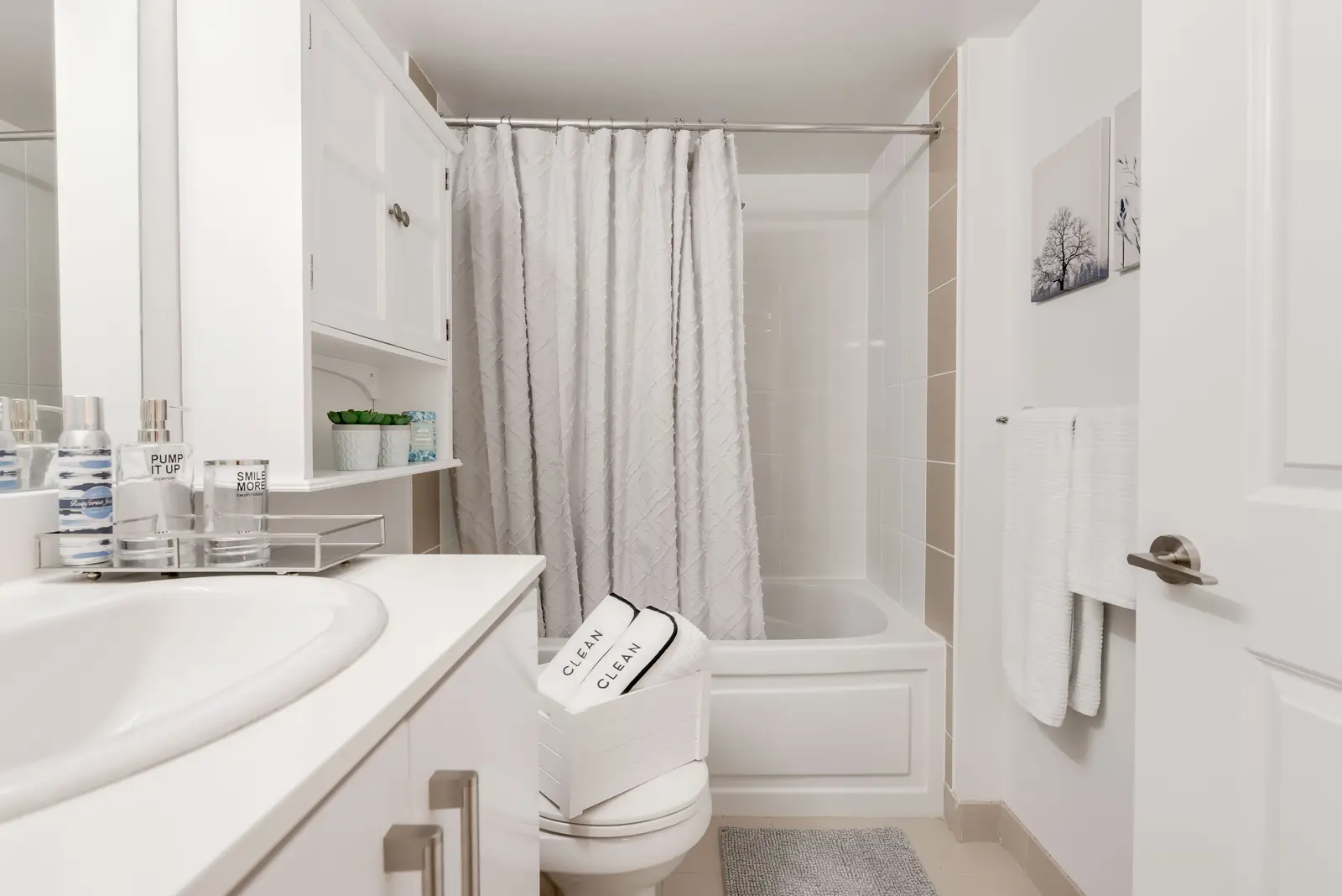 Interior of a North York condo, with a pale sofa, a white kitchen, and light wood floors.