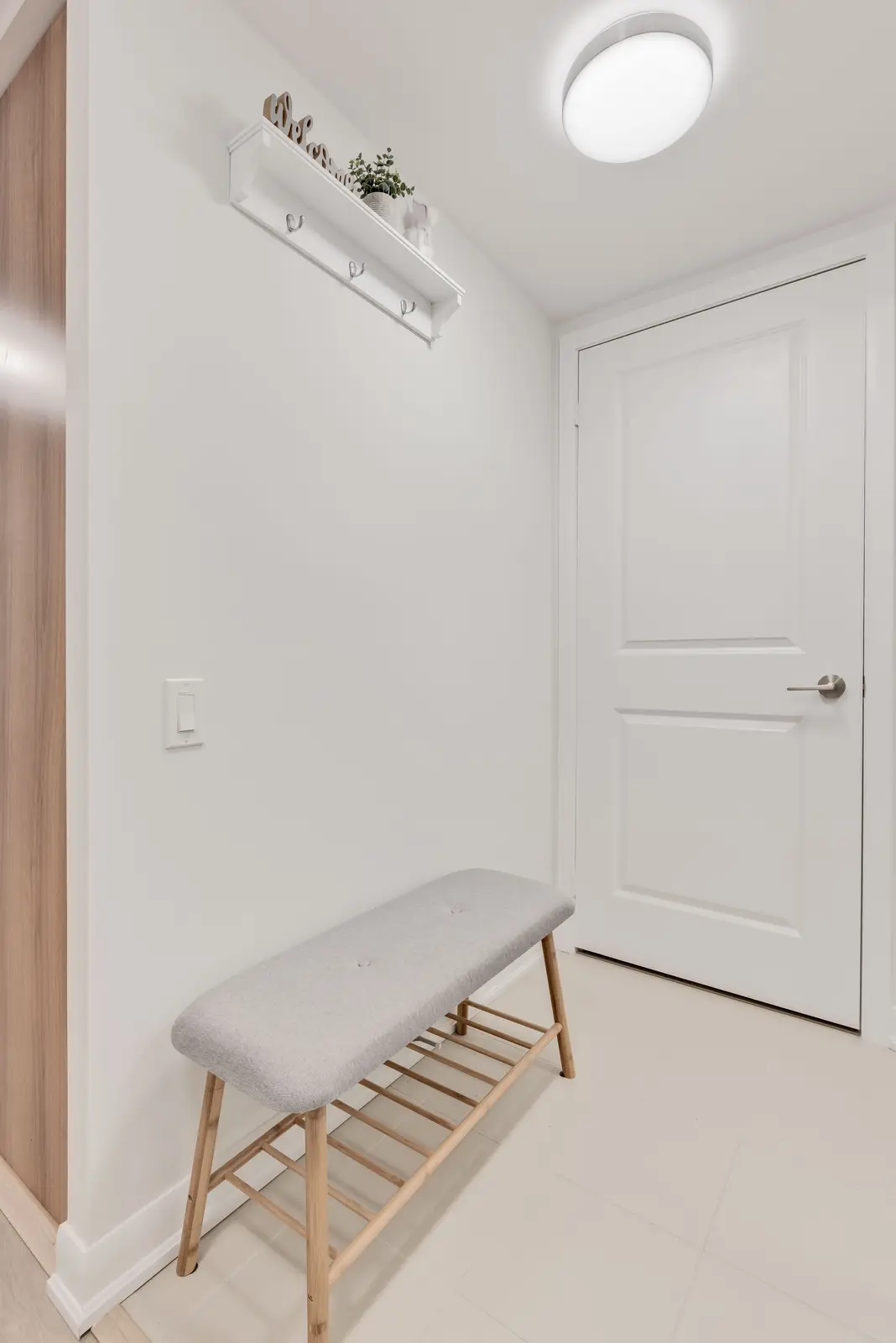 Interior of a North York condo, with a pale sofa, a white kitchen, and light wood floors.