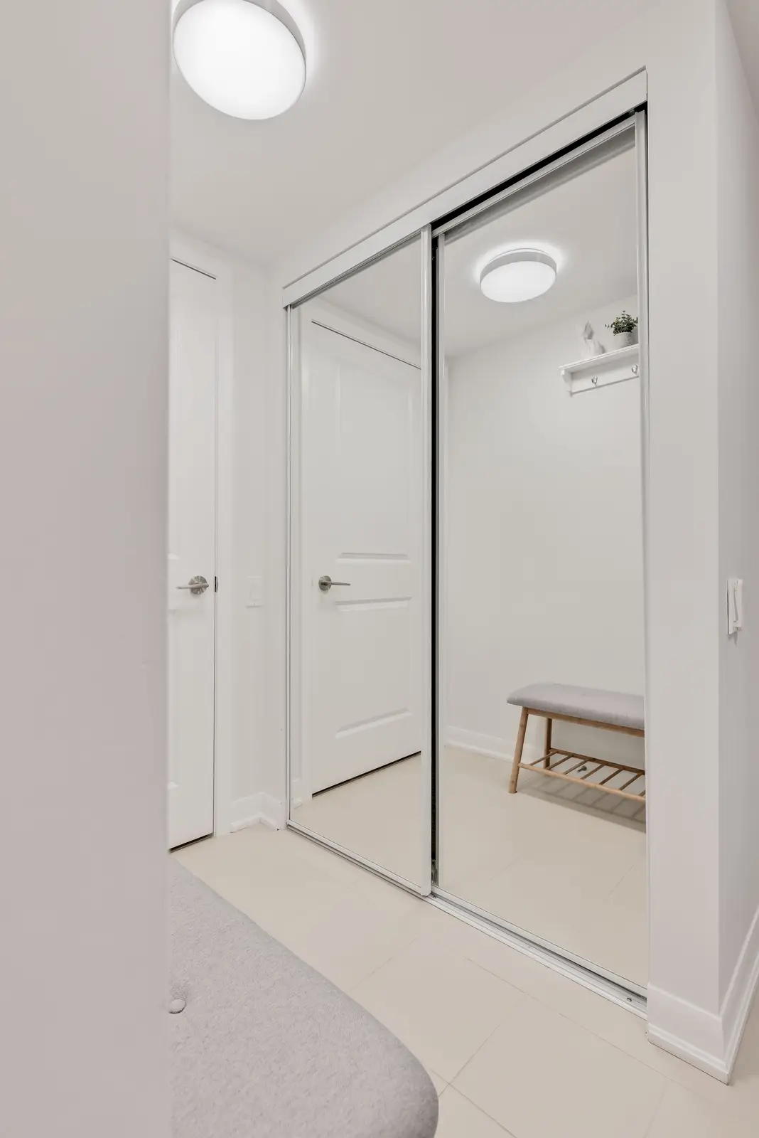 Interior of a North York condo, with a pale sofa, a white kitchen, and light wood floors.