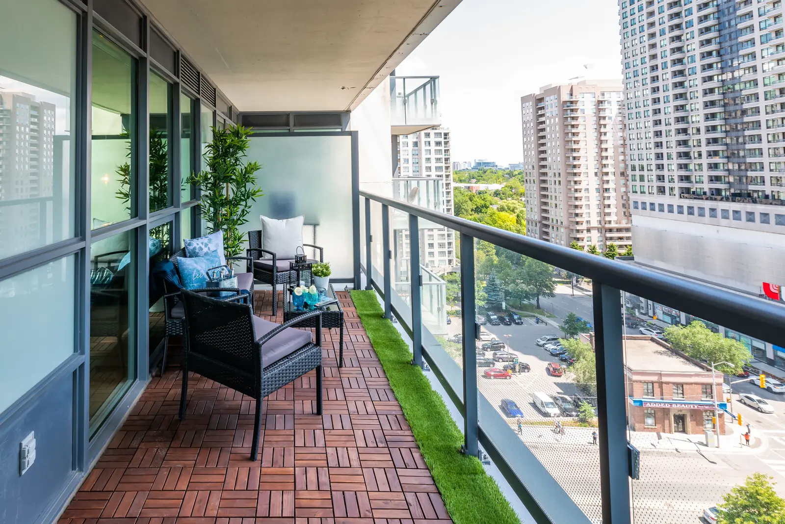 Interior of a North York condo, with a pale sofa, a white kitchen, and light wood floors.