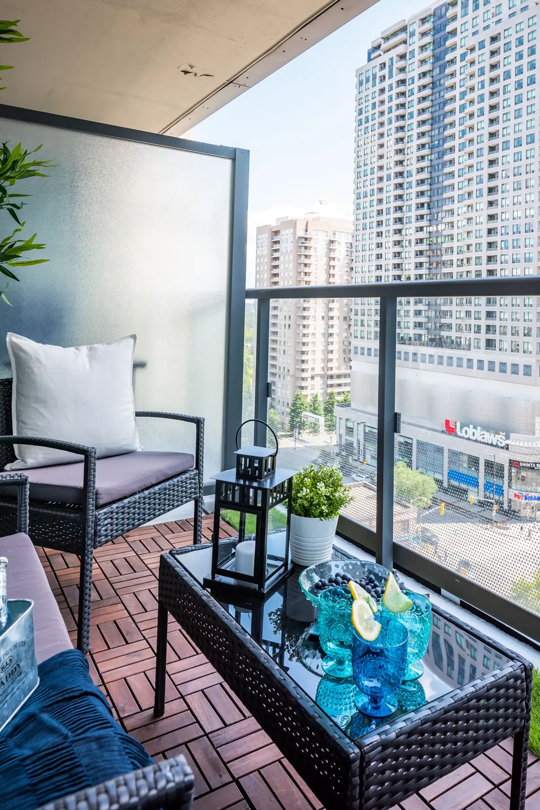Interior of a North York condo, with a pale sofa, a white kitchen, and light wood floors.