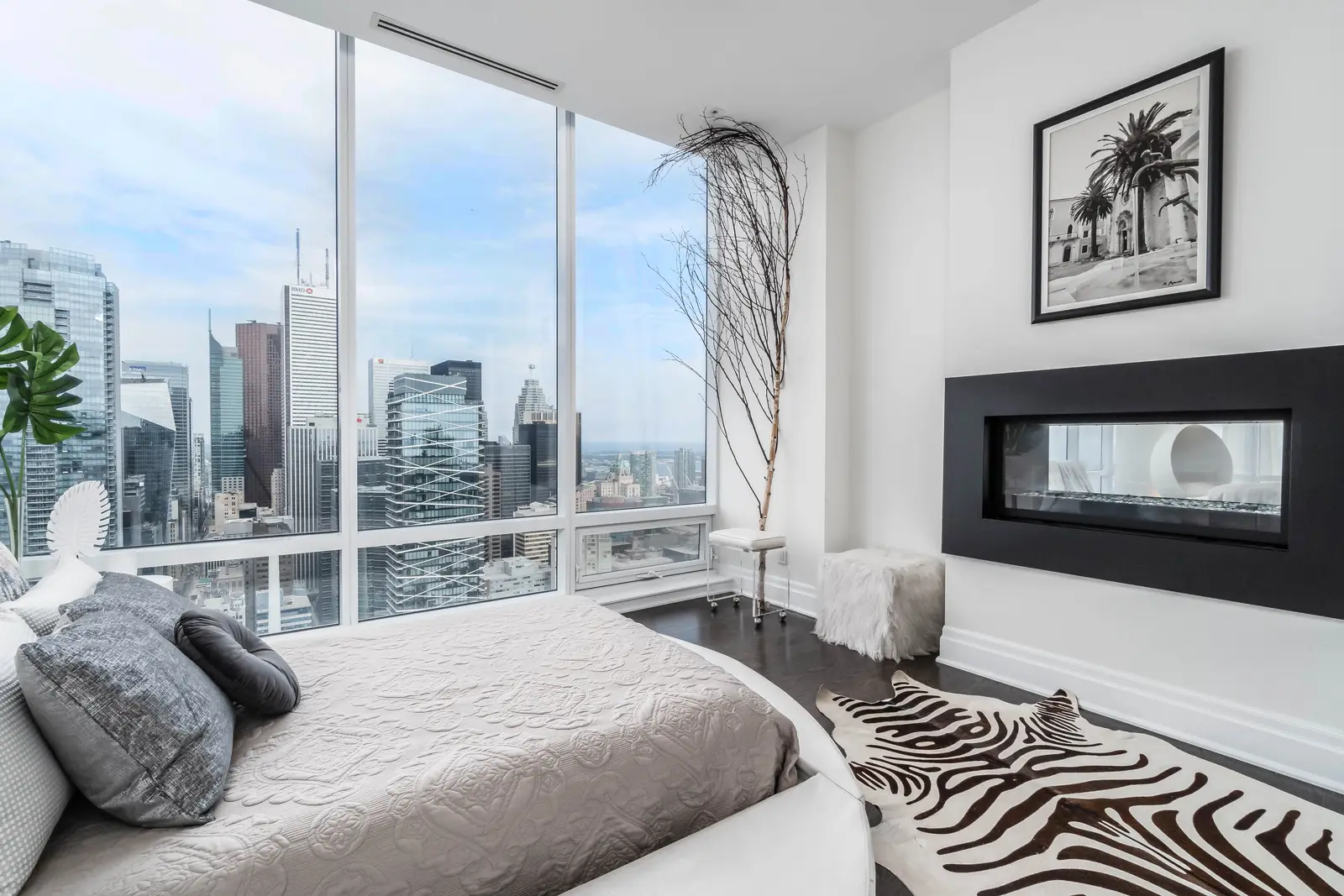 Interior of a condo on Adelaide Street West in Toronto, with purple chairs, a white living room, and the skyline beyond the glass.