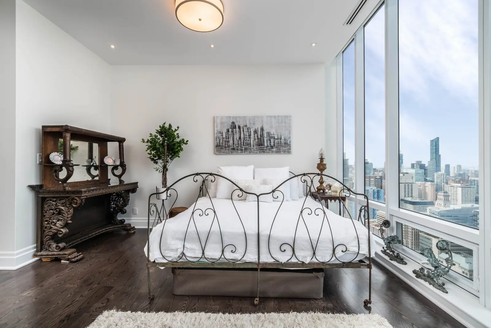 Interior of a condo on Adelaide Street West in Toronto, with purple chairs, a white living room, and the skyline beyond the glass.