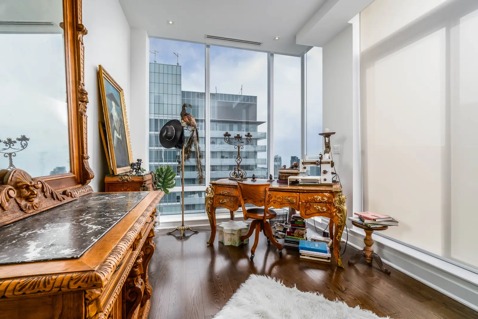 Interior of a condo on Adelaide Street West in Toronto, with purple chairs, a white living room, and the skyline beyond the glass.