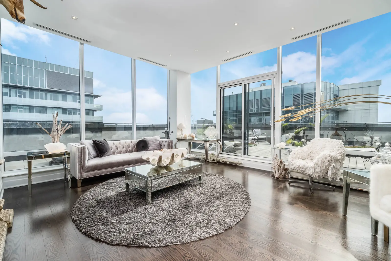 Interior of a condo on Adelaide Street West in Toronto, with purple chairs, a white living room, and the skyline beyond the glass.