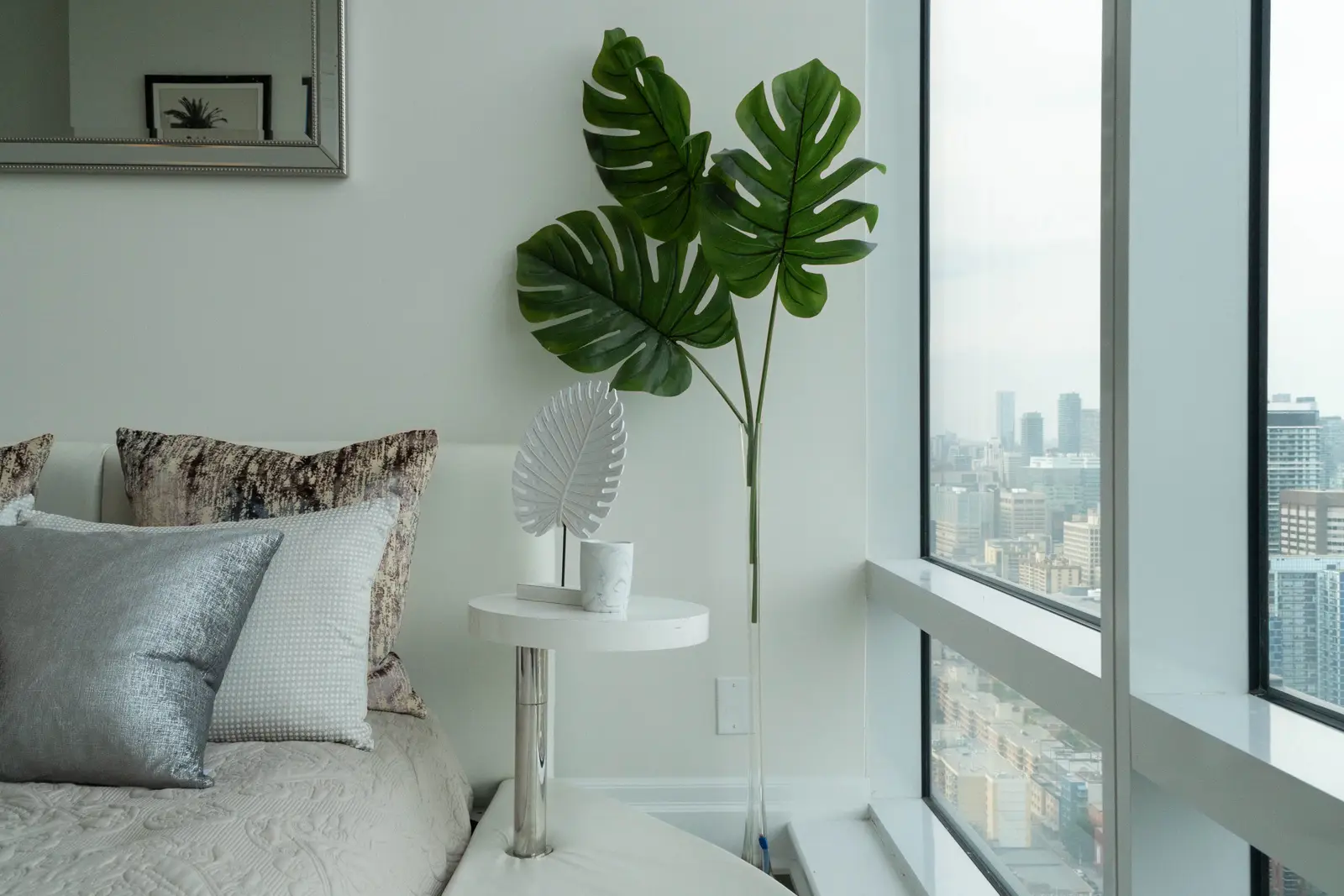 Interior of a condo on Adelaide Street West in Toronto, with purple chairs, a white living room, and the skyline beyond the glass.