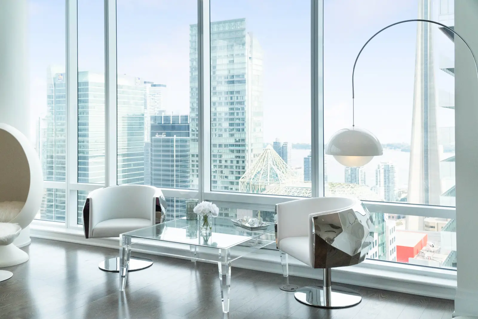 Interior of a condo on Adelaide Street West in Toronto, with purple chairs, a white living room, and the skyline beyond the glass.