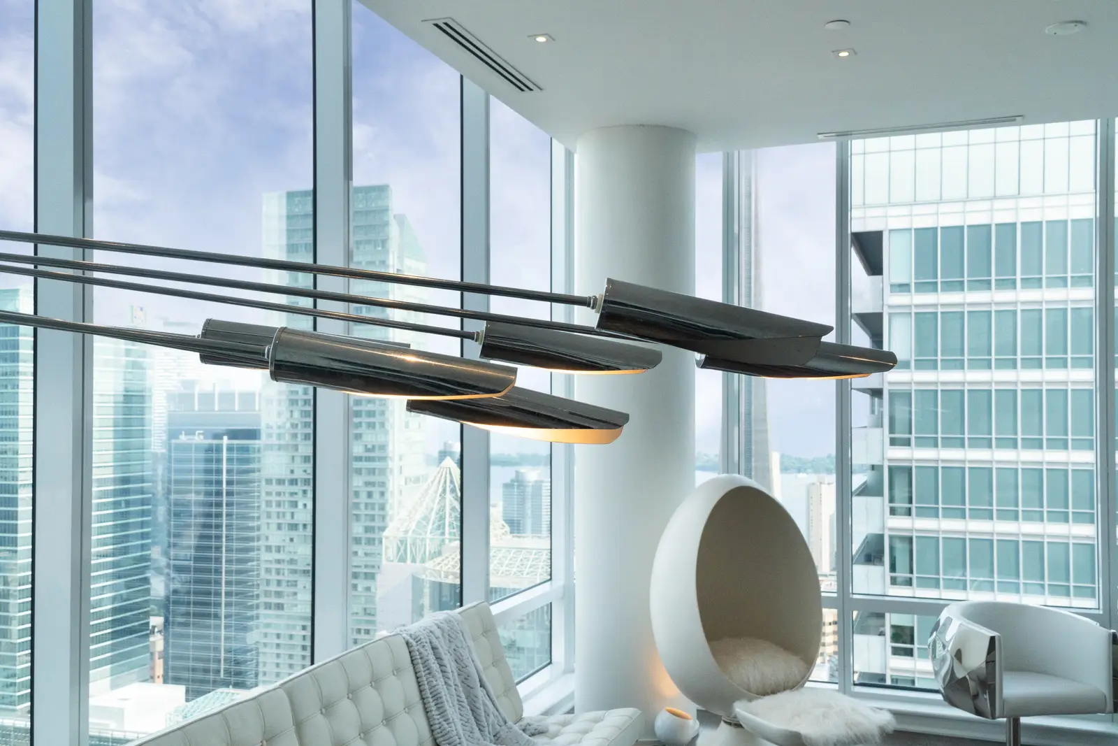 Interior of a condo on Adelaide Street West in Toronto, with purple chairs, a white living room, and the skyline beyond the glass.