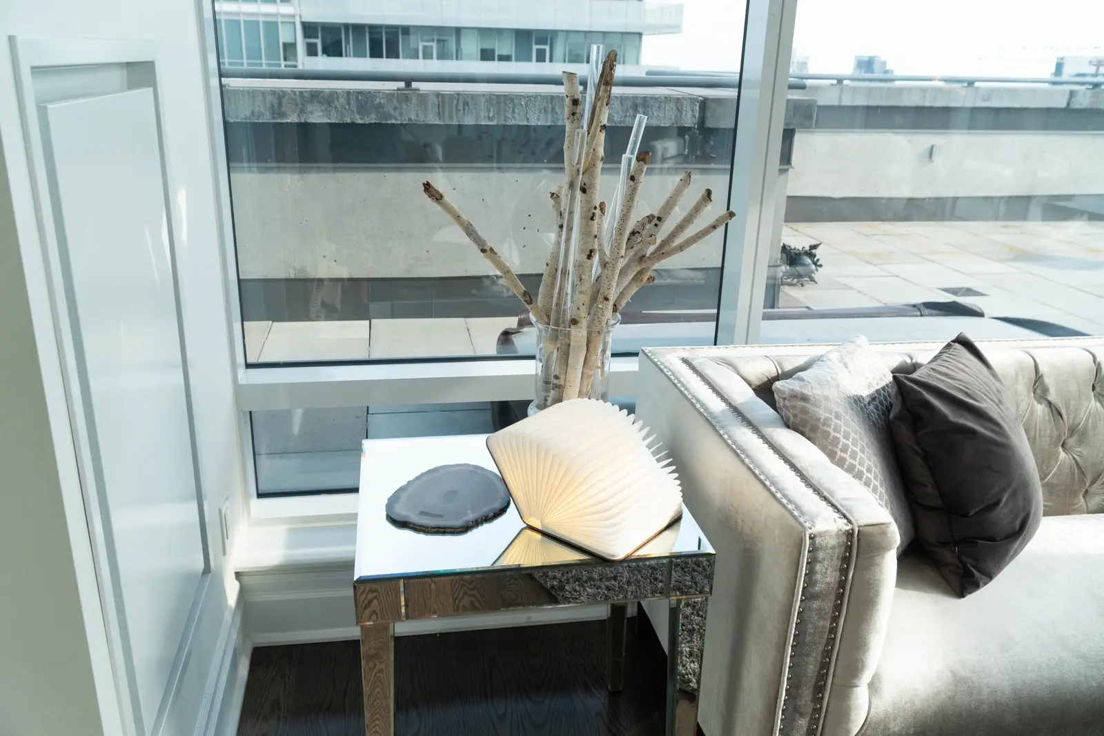 Interior of a condo on Adelaide Street West in Toronto, with purple chairs, a white living room, and the skyline beyond the glass.