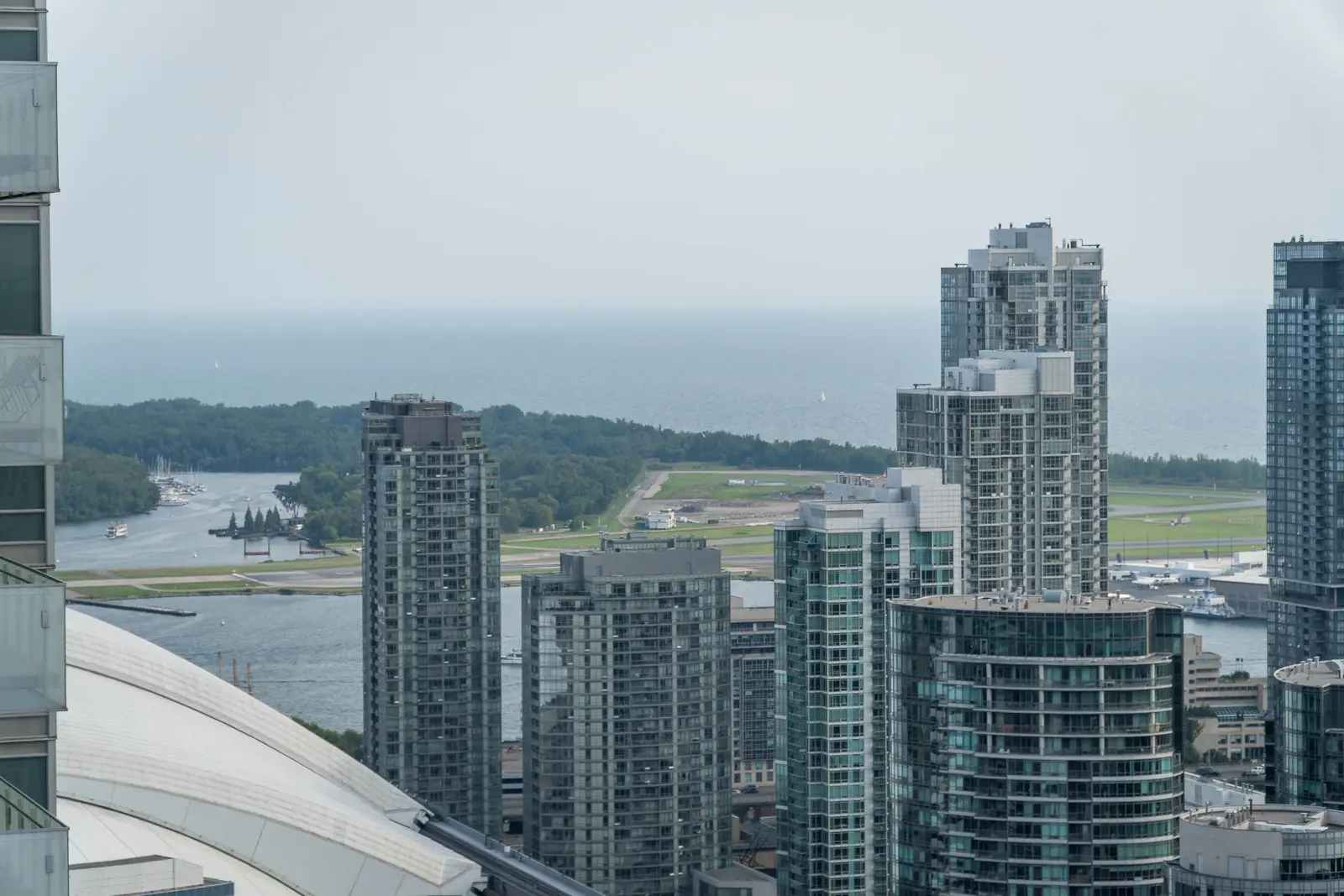 Interior of a condo on Adelaide Street West in Toronto, with purple chairs, a white living room, and the skyline beyond the glass.