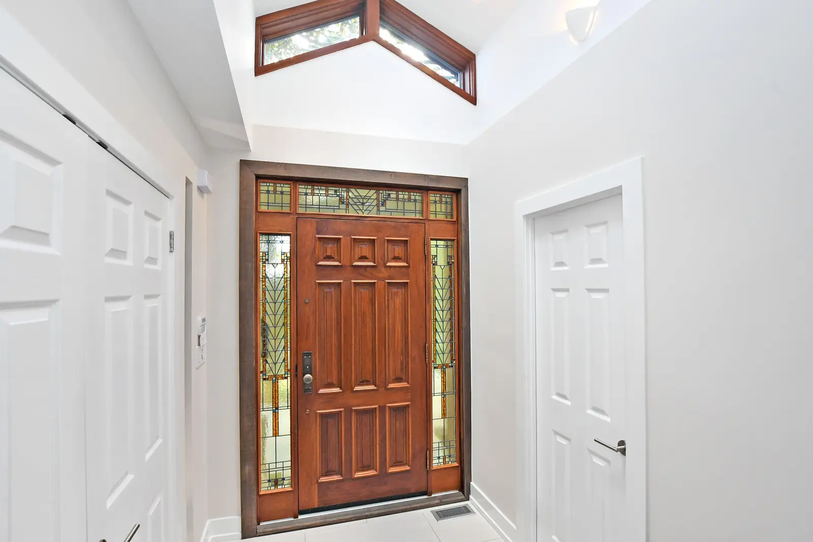 Interior of a house on Plymbridge Road in North York, with wood floors, a white kitchen, and windows onto the trees.
