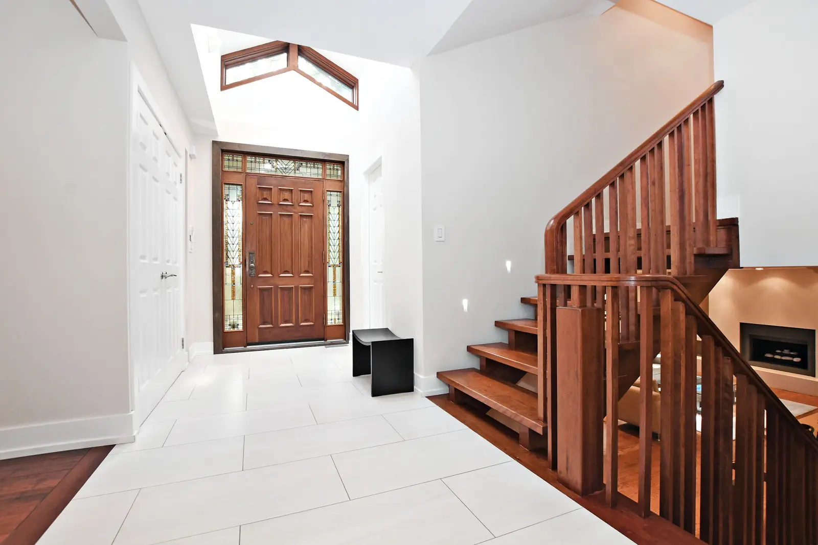Interior of a house on Plymbridge Road in North York, with wood floors, a white kitchen, and windows onto the trees.