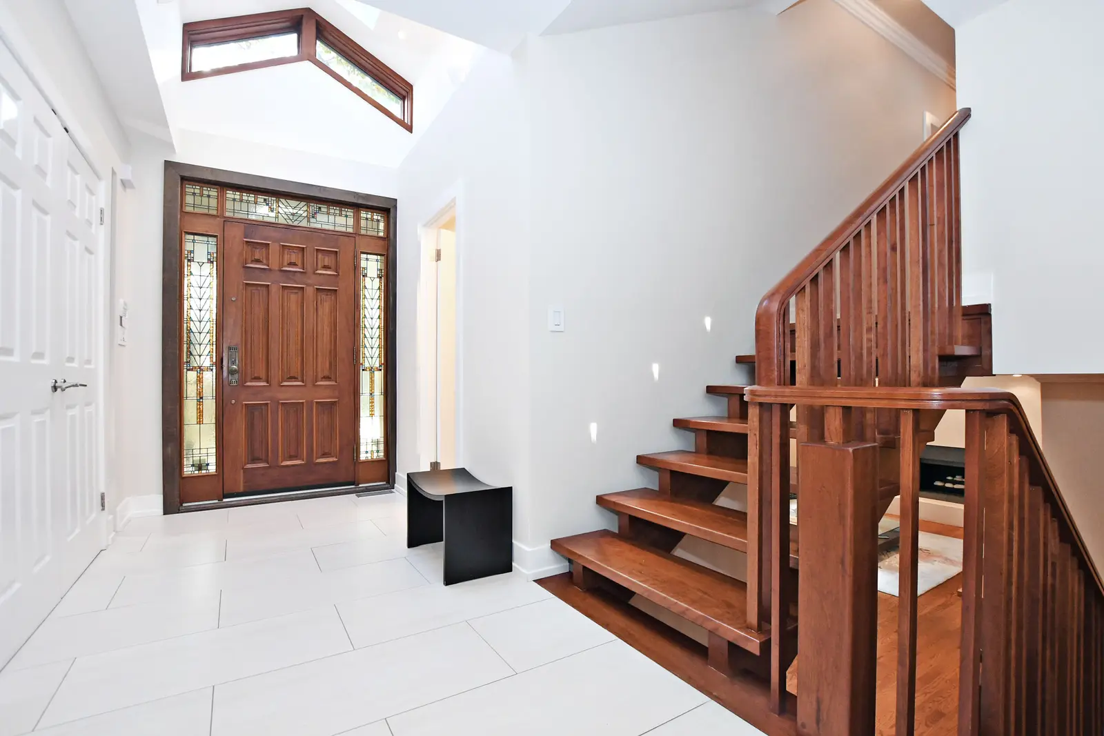 Interior of a house on Plymbridge Road in North York, with wood floors, a white kitchen, and windows onto the trees.