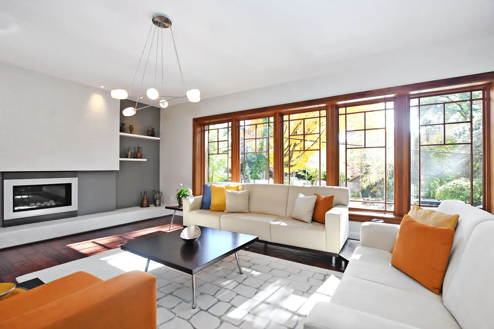 Interior of a house on Plymbridge Road in North York, with wood floors, a white kitchen, and windows onto the trees.
