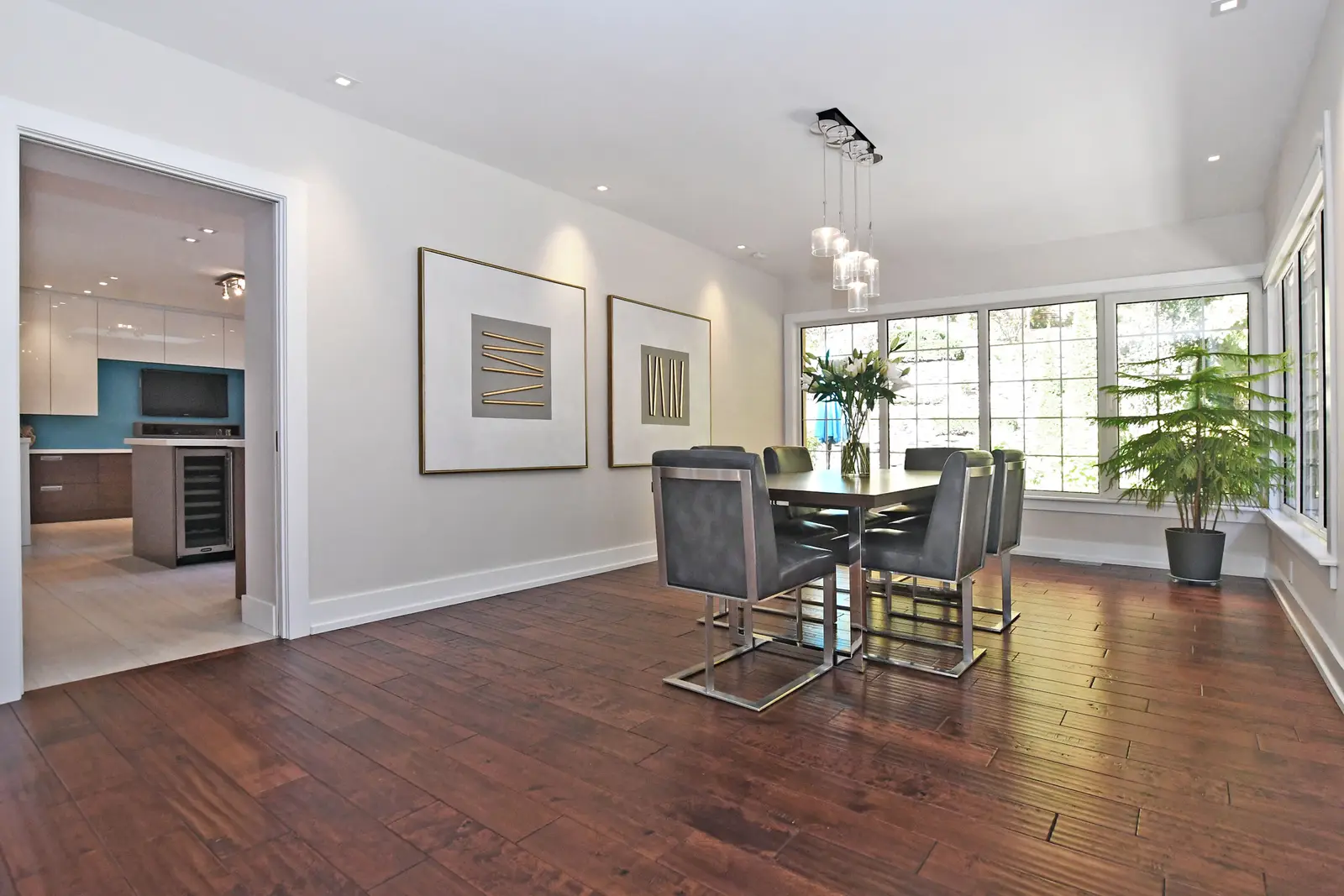 Interior of a house on Plymbridge Road in North York, with wood floors, a white kitchen, and windows onto the trees.