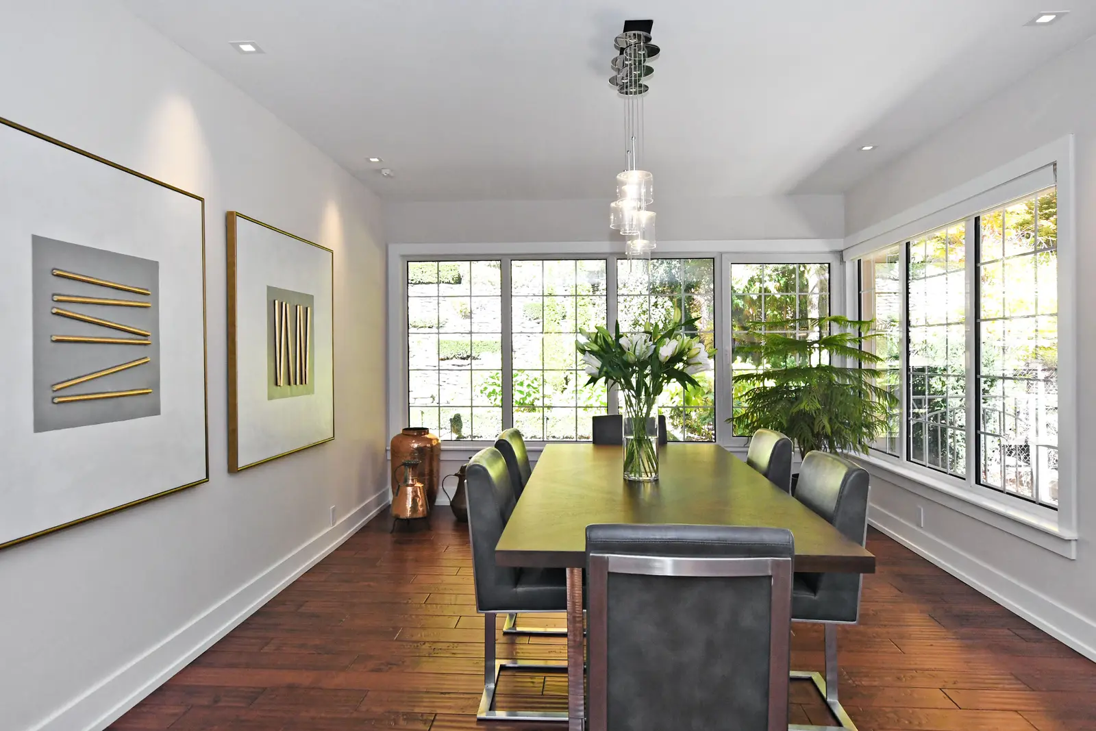 Interior of a house on Plymbridge Road in North York, with wood floors, a white kitchen, and windows onto the trees.