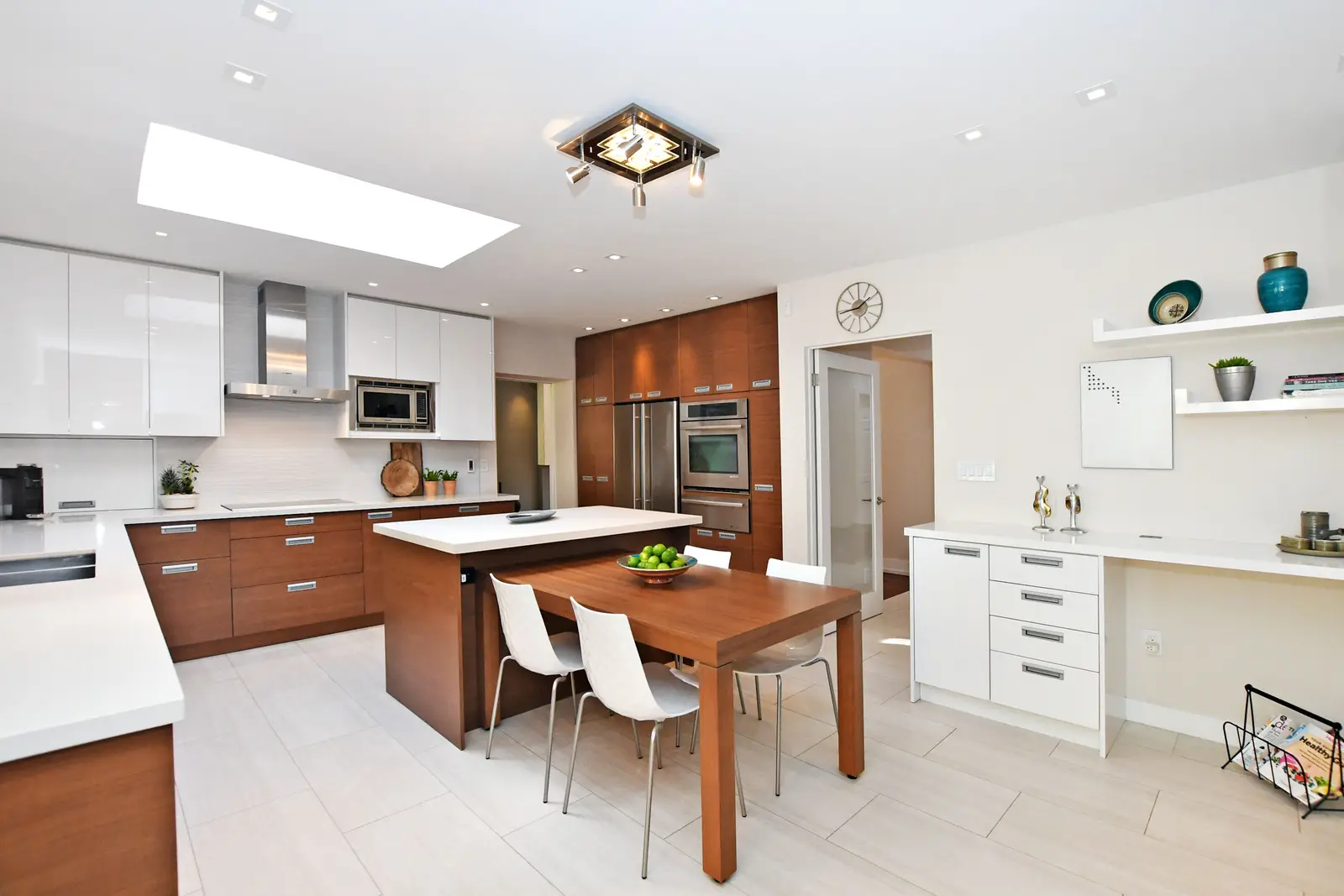 Interior of a house on Plymbridge Road in North York, with wood floors, a white kitchen, and windows onto the trees.