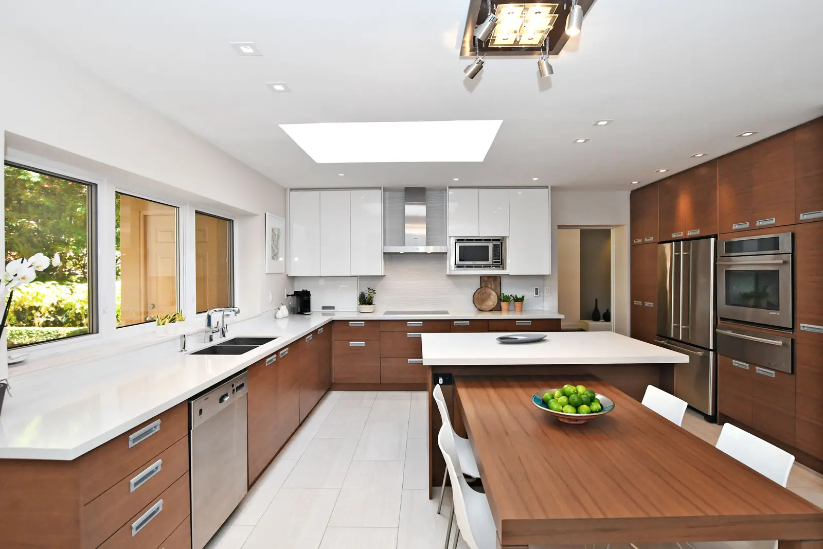 Interior of a house on Plymbridge Road in North York, with wood floors, a white kitchen, and windows onto the trees.