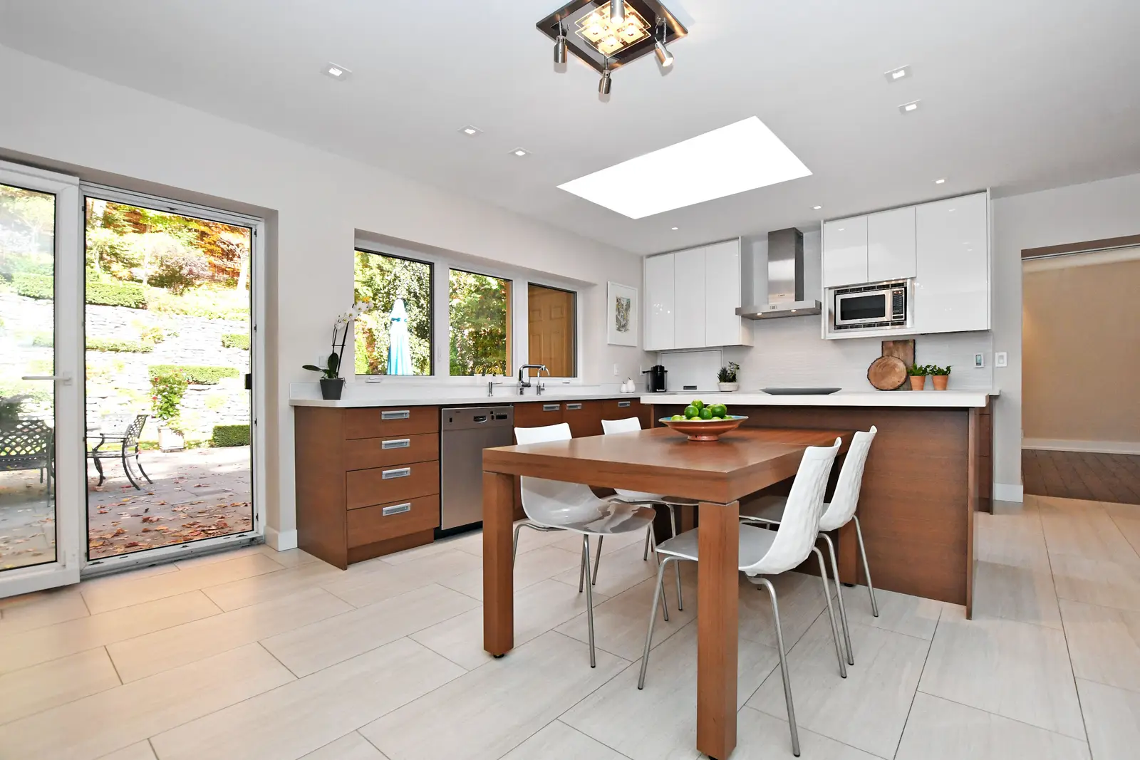 Interior of a house on Plymbridge Road in North York, with wood floors, a white kitchen, and windows onto the trees.