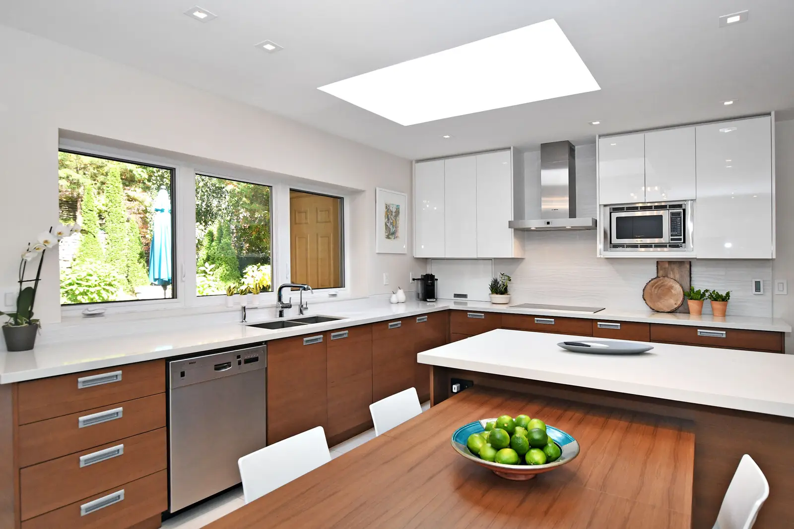 Interior of a house on Plymbridge Road in North York, with wood floors, a white kitchen, and windows onto the trees.