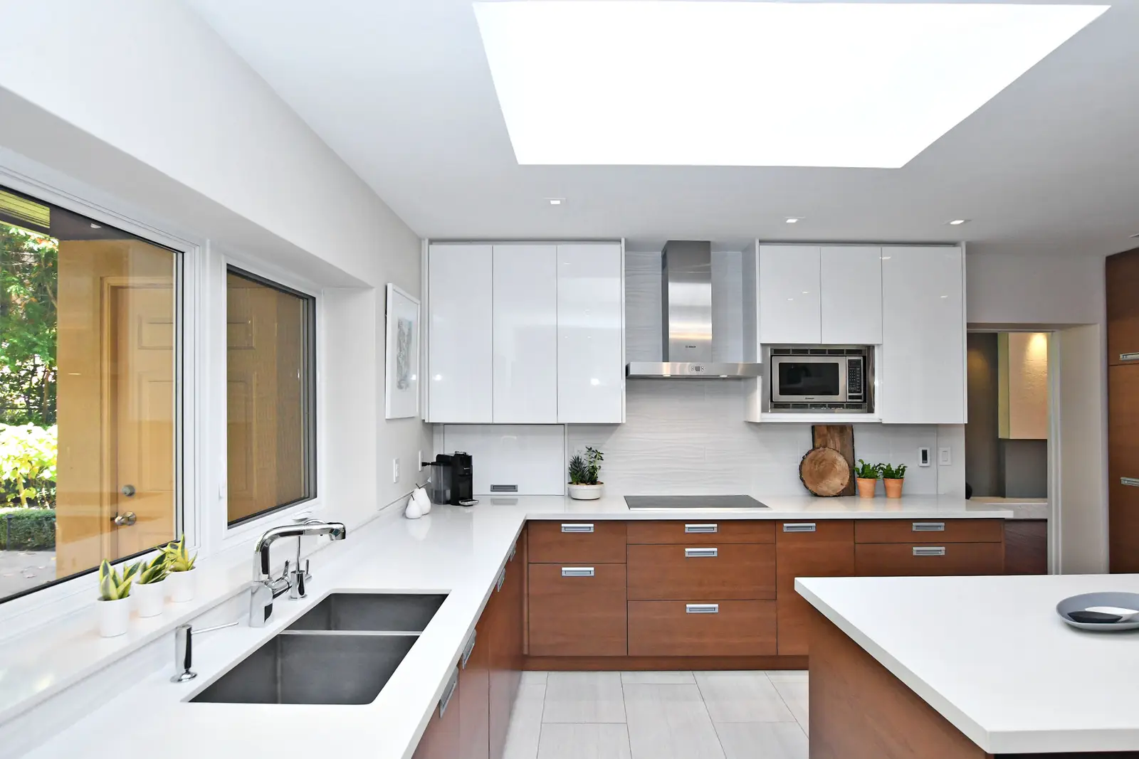 Interior of a house on Plymbridge Road in North York, with wood floors, a white kitchen, and windows onto the trees.