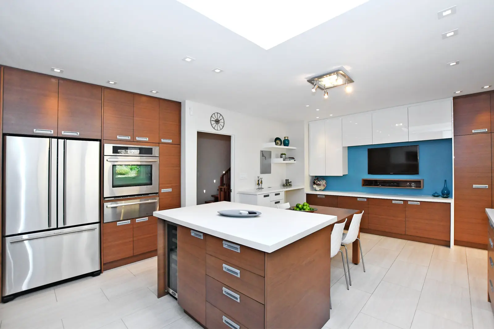 Interior of a house on Plymbridge Road in North York, with wood floors, a white kitchen, and windows onto the trees.