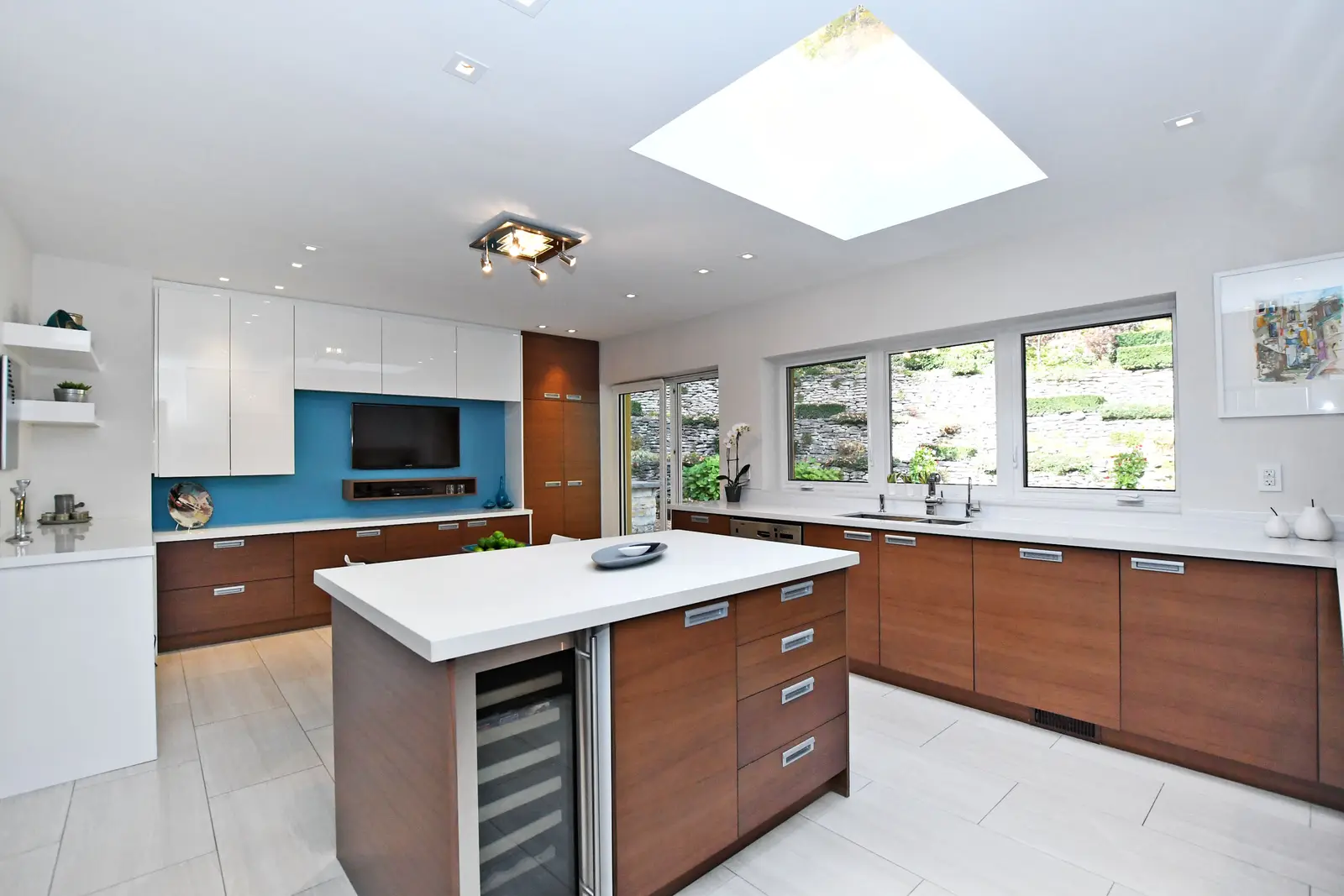 Interior of a house on Plymbridge Road in North York, with wood floors, a white kitchen, and windows onto the trees.