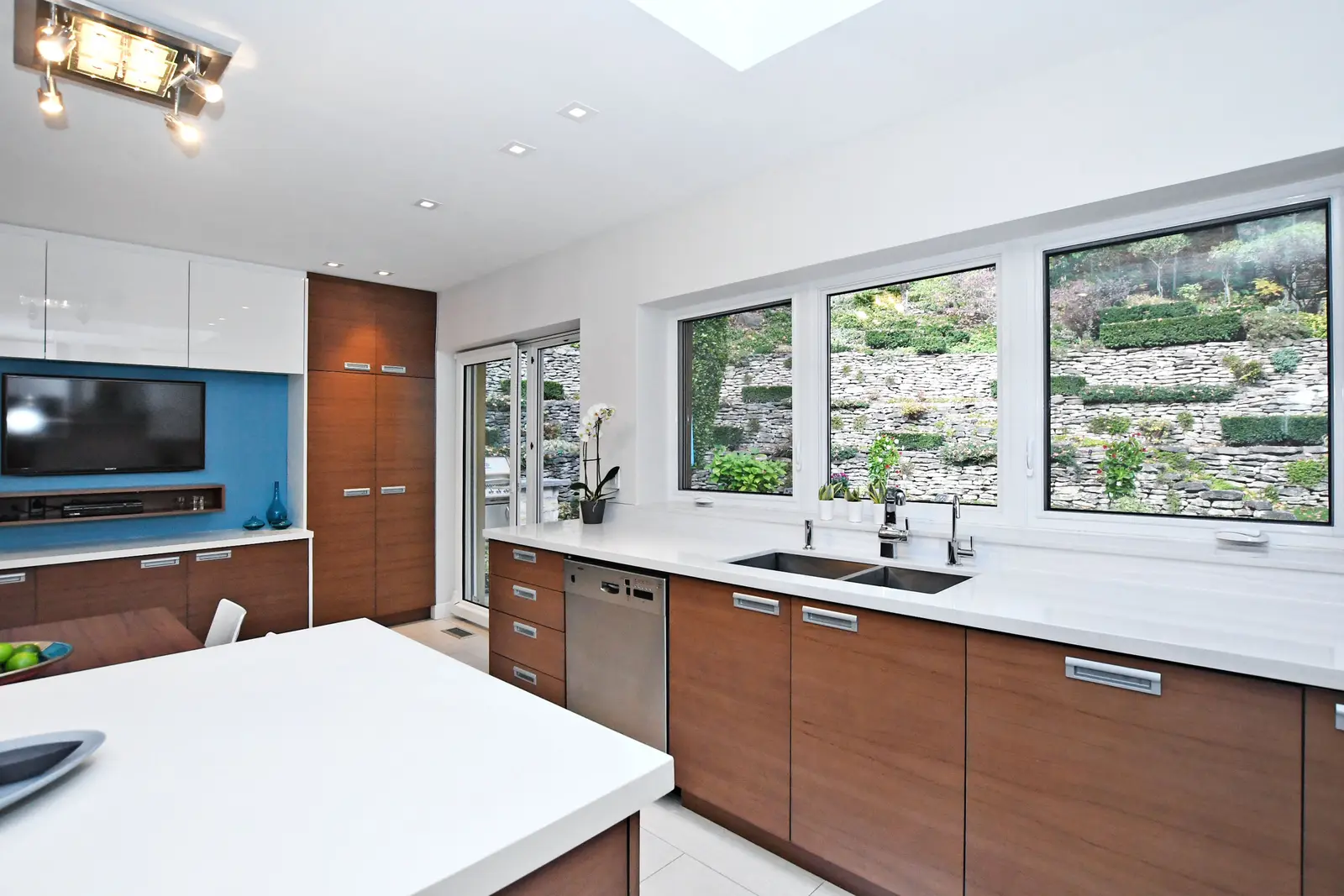 Interior of a house on Plymbridge Road in North York, with wood floors, a white kitchen, and windows onto the trees.