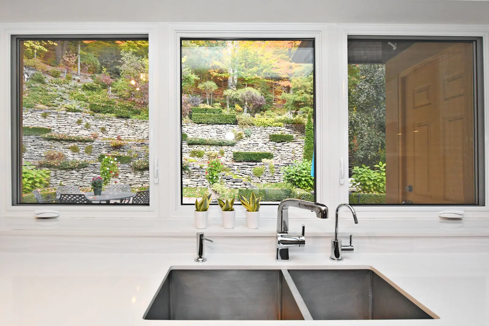Interior of a house on Plymbridge Road in North York, with wood floors, a white kitchen, and windows onto the trees.